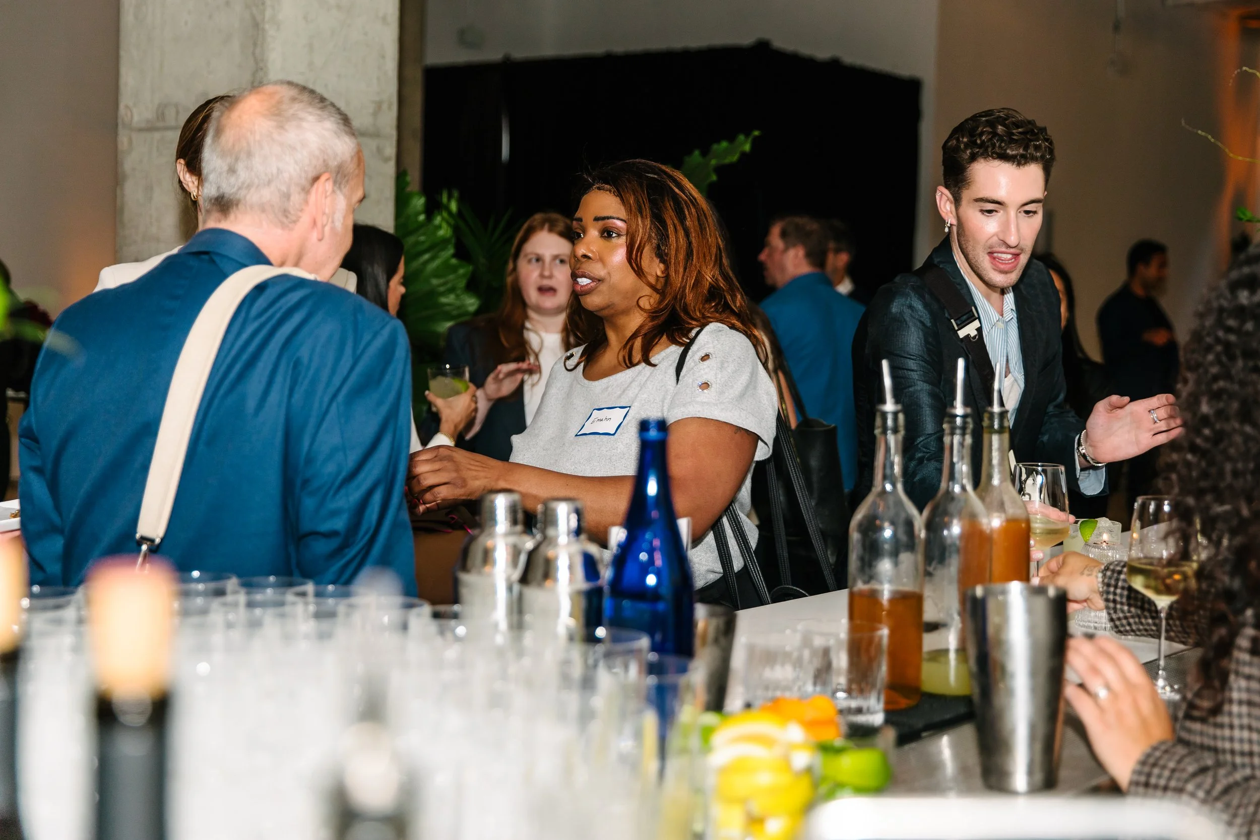 Alt text: Close-up of a bar counter with bottles and glasses, with a group of people in the background at one of Resident’s company retreat venues.