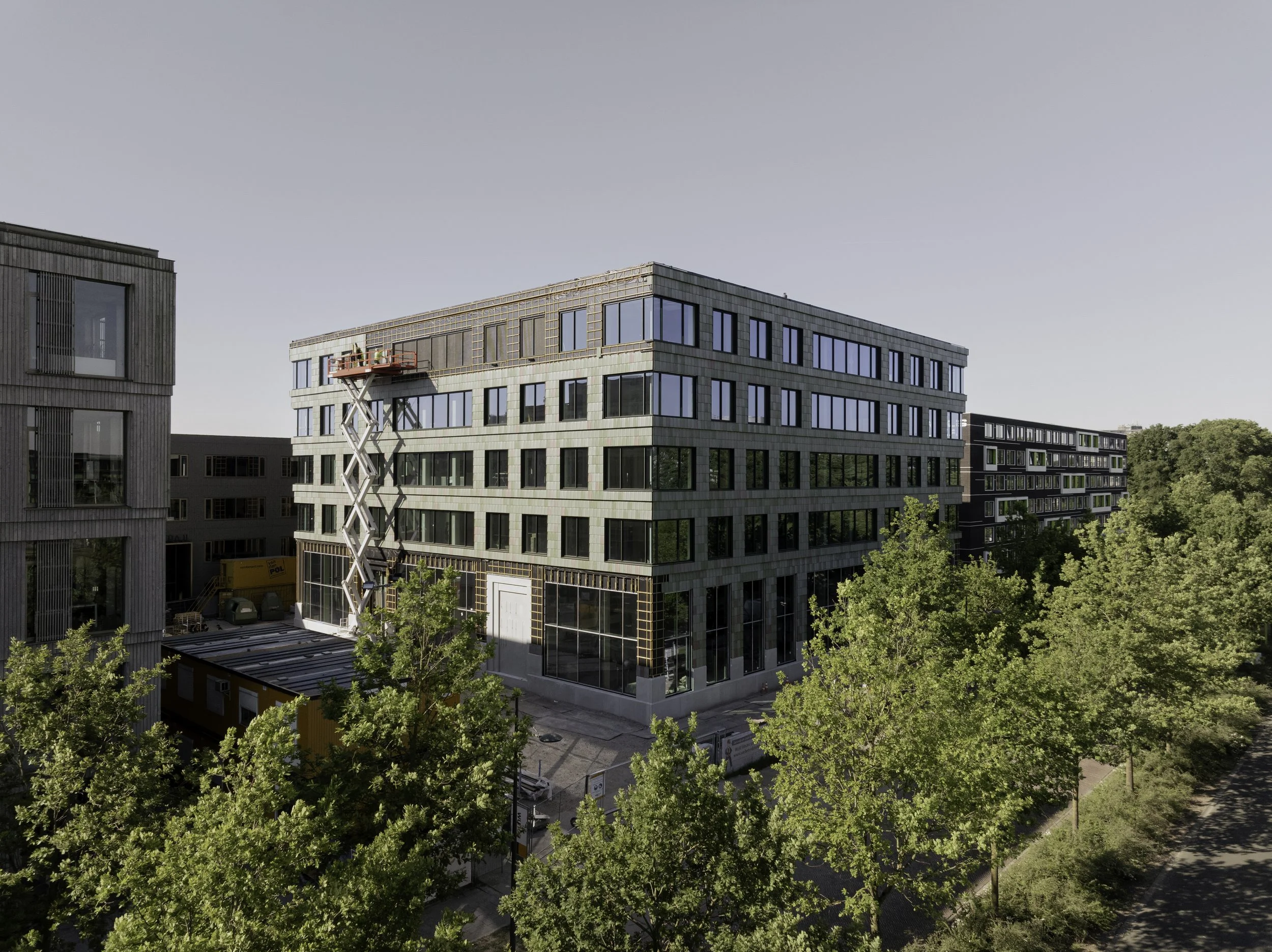 Façade in progress at Plus Ultra III, with ongoing installation of the recycled cladding system. This construction-phase image clearly shows the modular application of Pretty Plastic’s Basic Third tiles and the integration of large window elements.