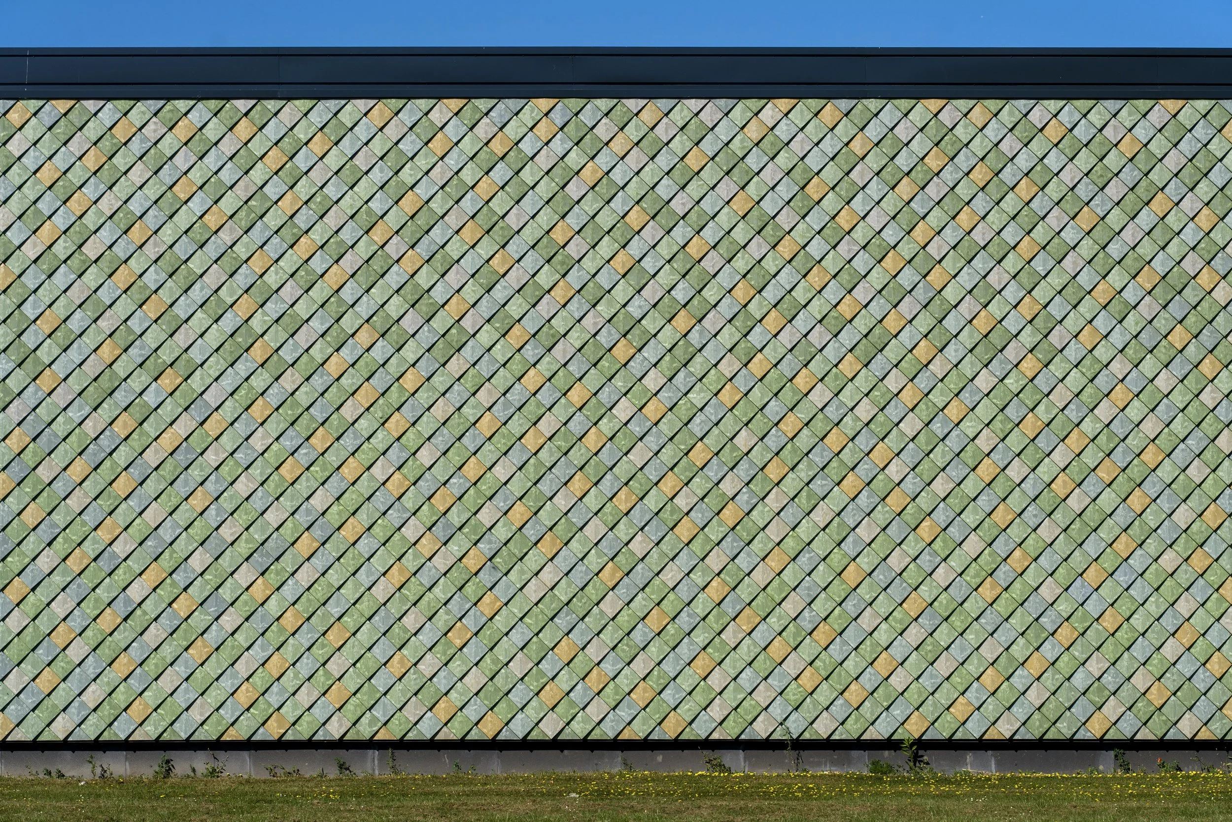 Warm ochre tones meet natural green in this circular façade design – Pretty Plastic cladding at Lensen.