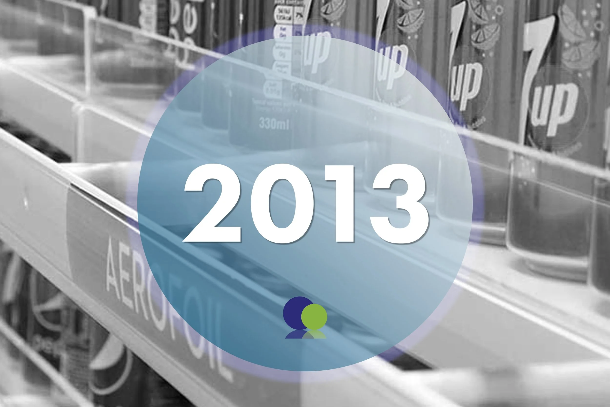 Un rayon d'épicerie rempli de canettes et de bouteilles de boissons, avec un grand panneau affichant l'année 2013.