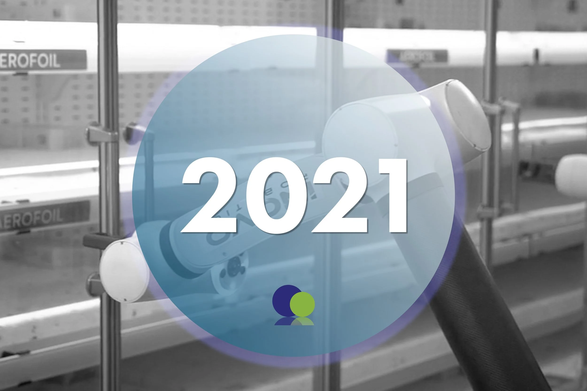 Une superposition numérique avec l'année 2021 et un petit graphique de deux cercles superposés, l'un bleu foncé et l'autre vert clair, devant un cadre industriel ou d'entrepôt flou avec des étagères et des boîtes, et un lecteur de codes-barres manuel.