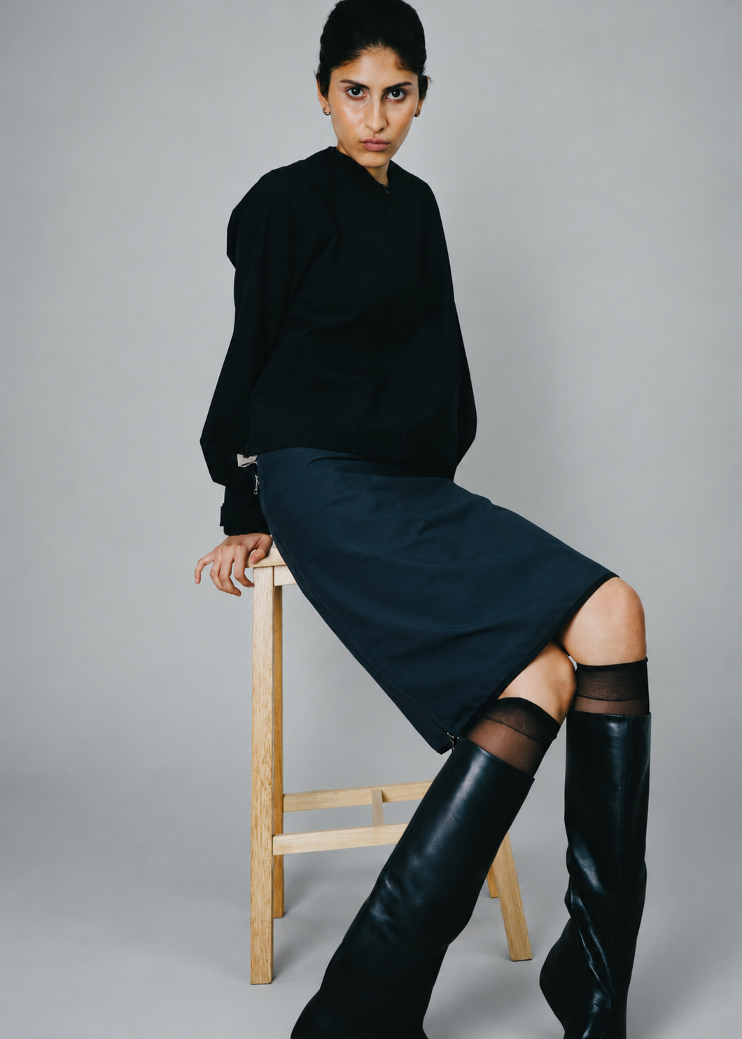 Model on stool against gray backdrop.png
