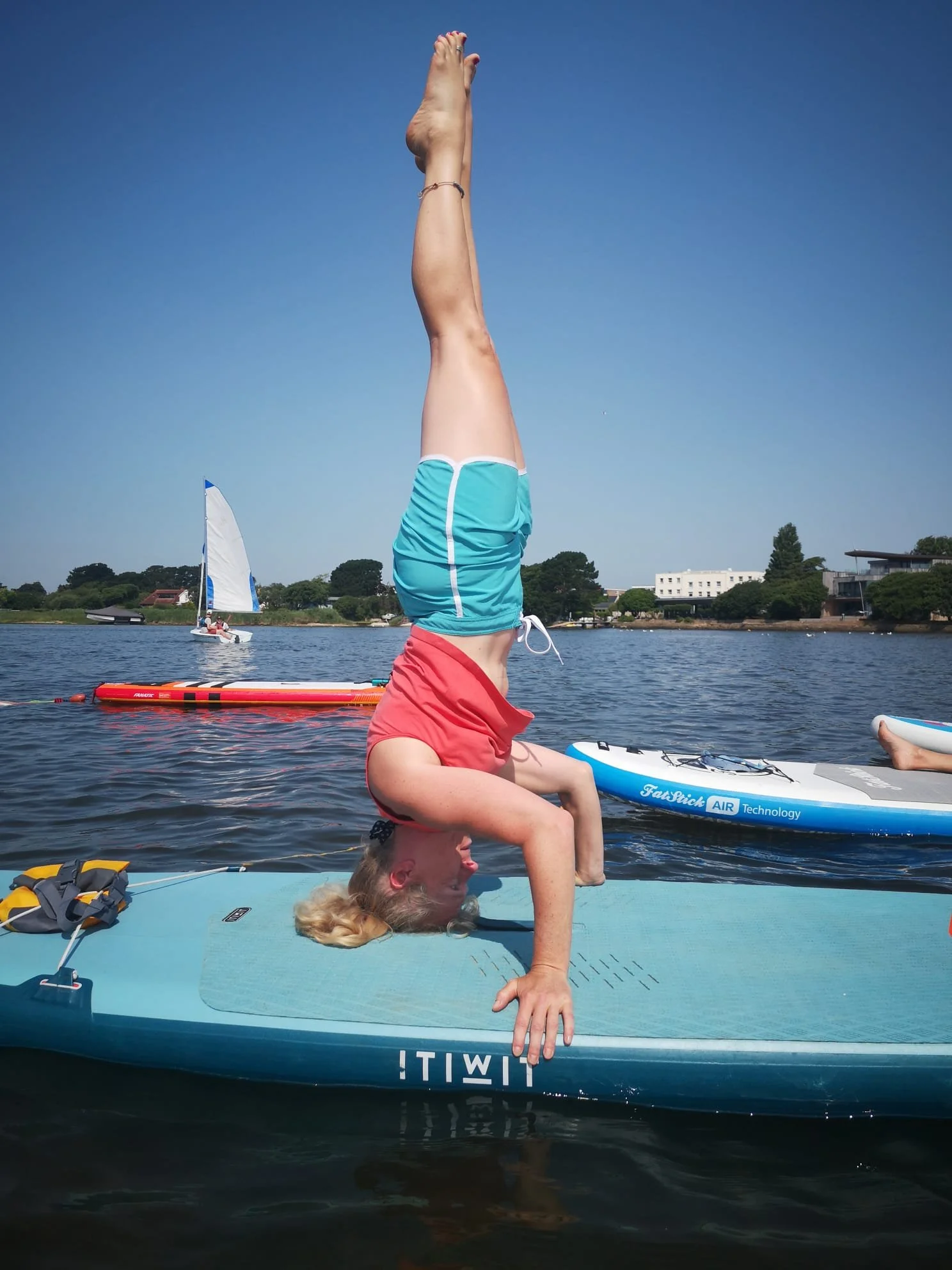 Person performing a headstand on a paddleboard on a lake