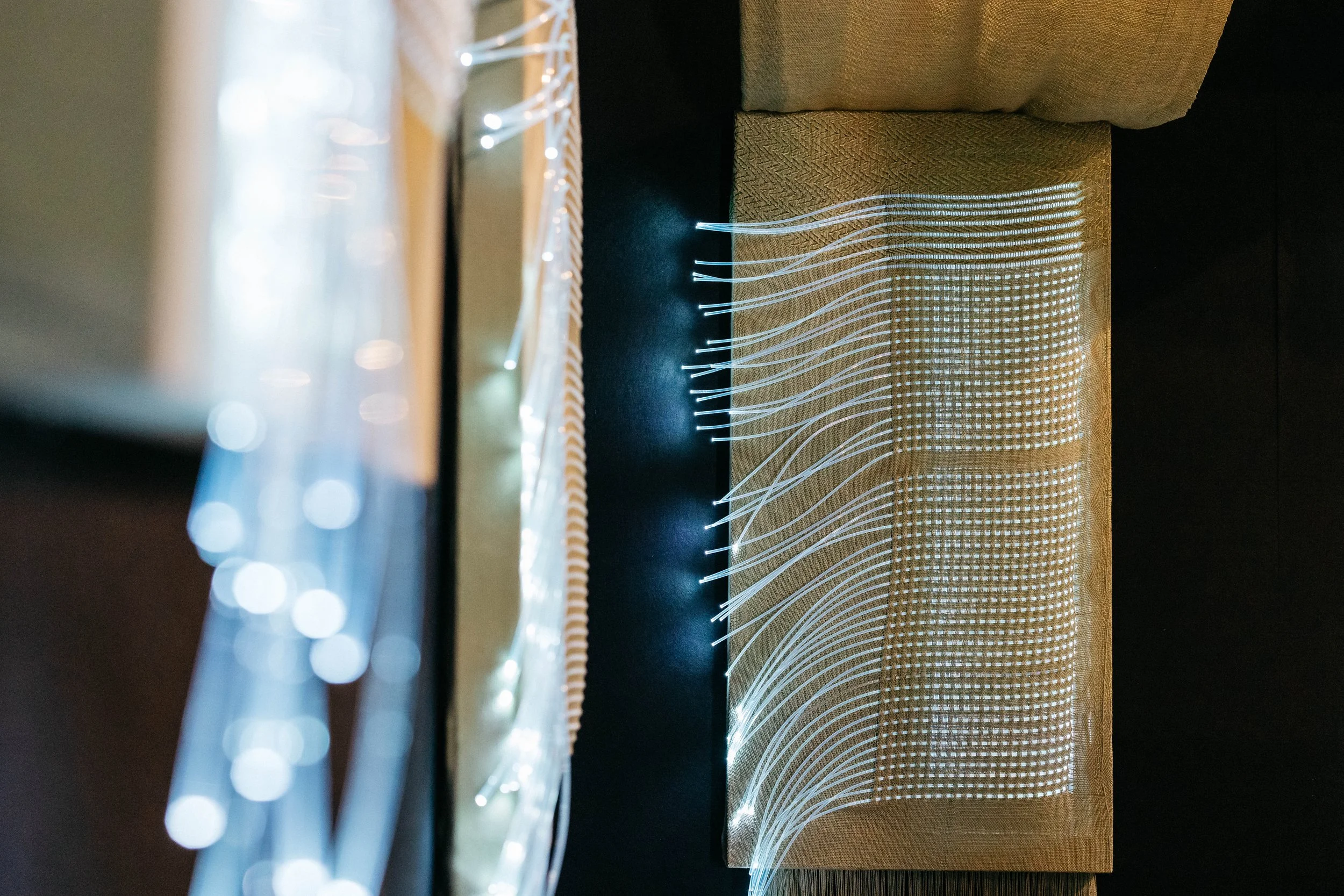 Craftwork Ancient Futures detail, fiber optic threads woven into fabric glowing in a grid pattern of light