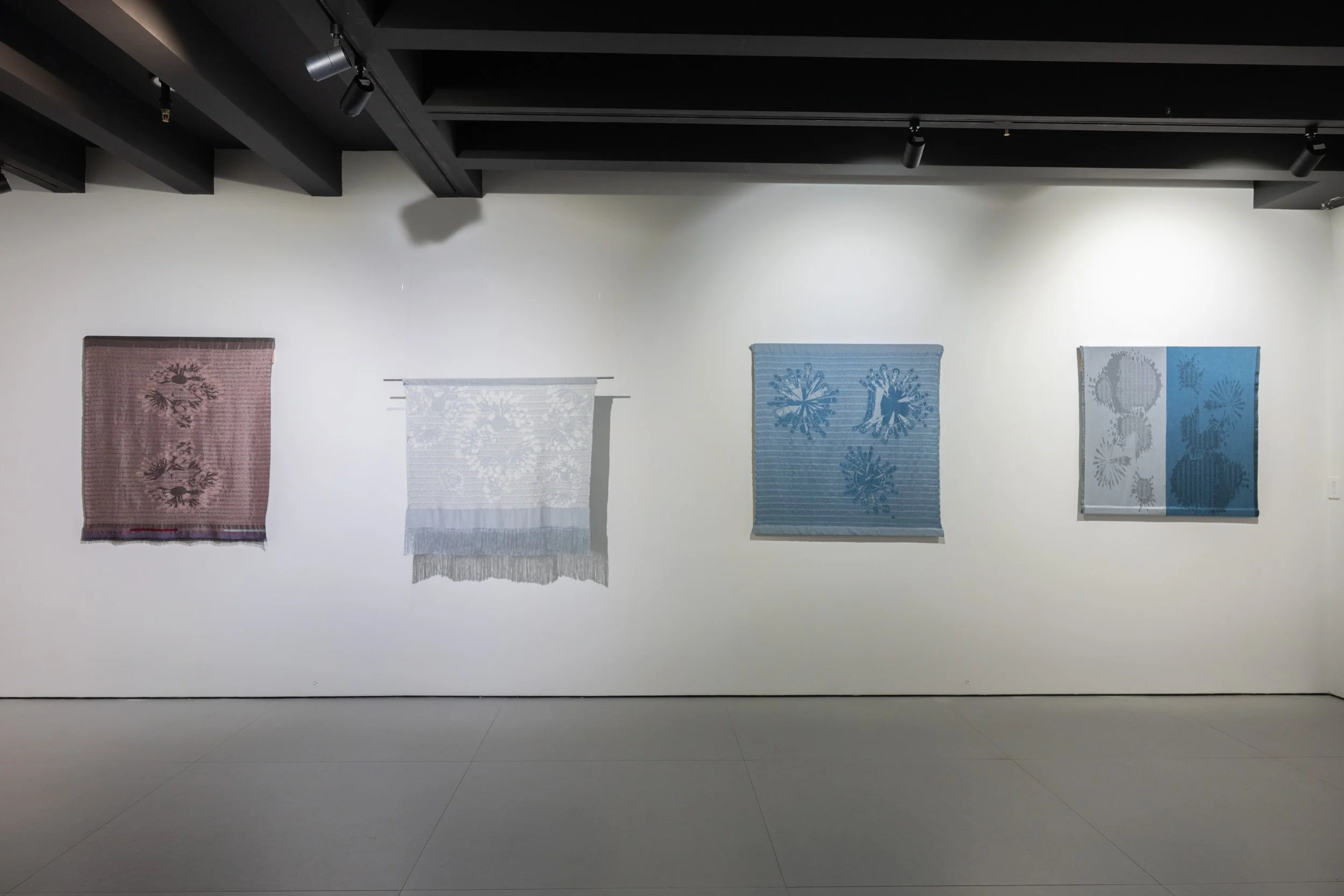 Slow Medium installation at THE BLANC, four woven textile panels in  pink, white, and blue showing lichen growth patterns, by Craftwork