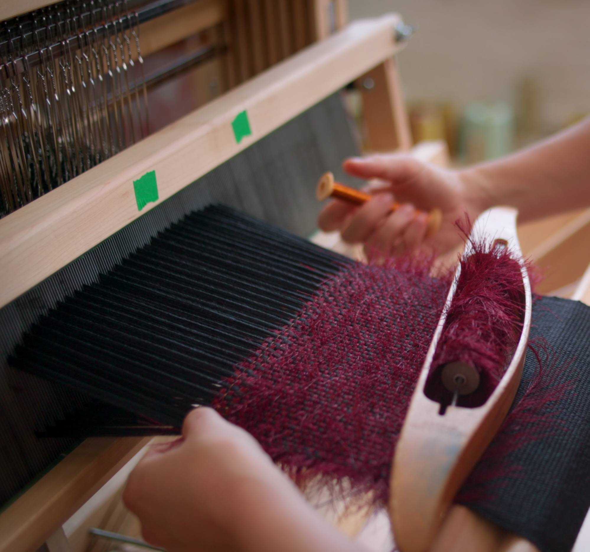 Weaving the Cycle Circle Cycle Coil soft speaker on a floor loom, holding a spool of copper magnet wire and a boat shuttle