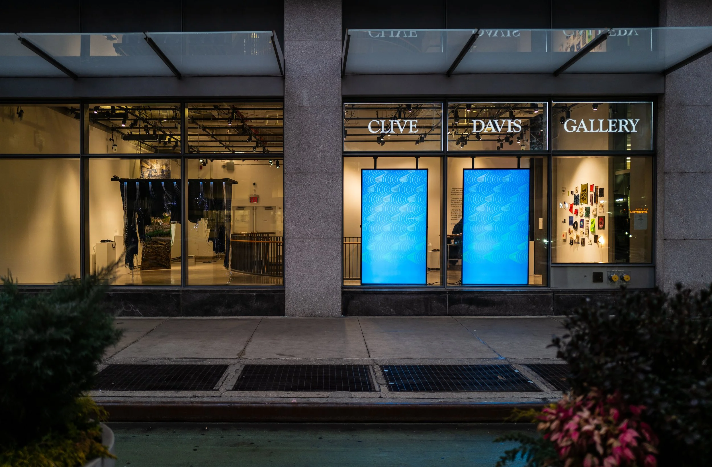 Clive Davis Gallery storefront at dusk, with two glowing blue screens of wave-like arches in the windows.