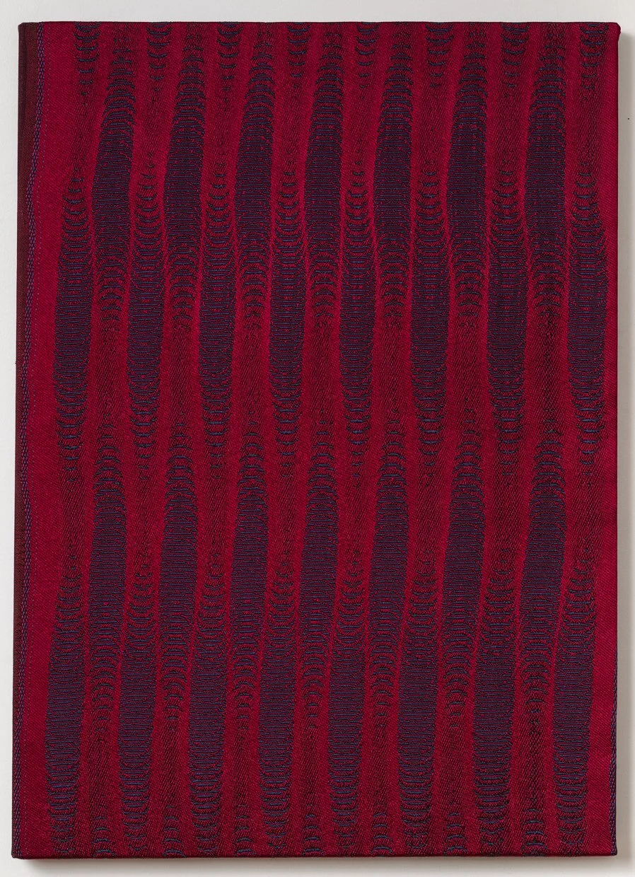 Framed crimson woven textile with vertical columns of dark navy crescents that swell and narrow like rippling waves.