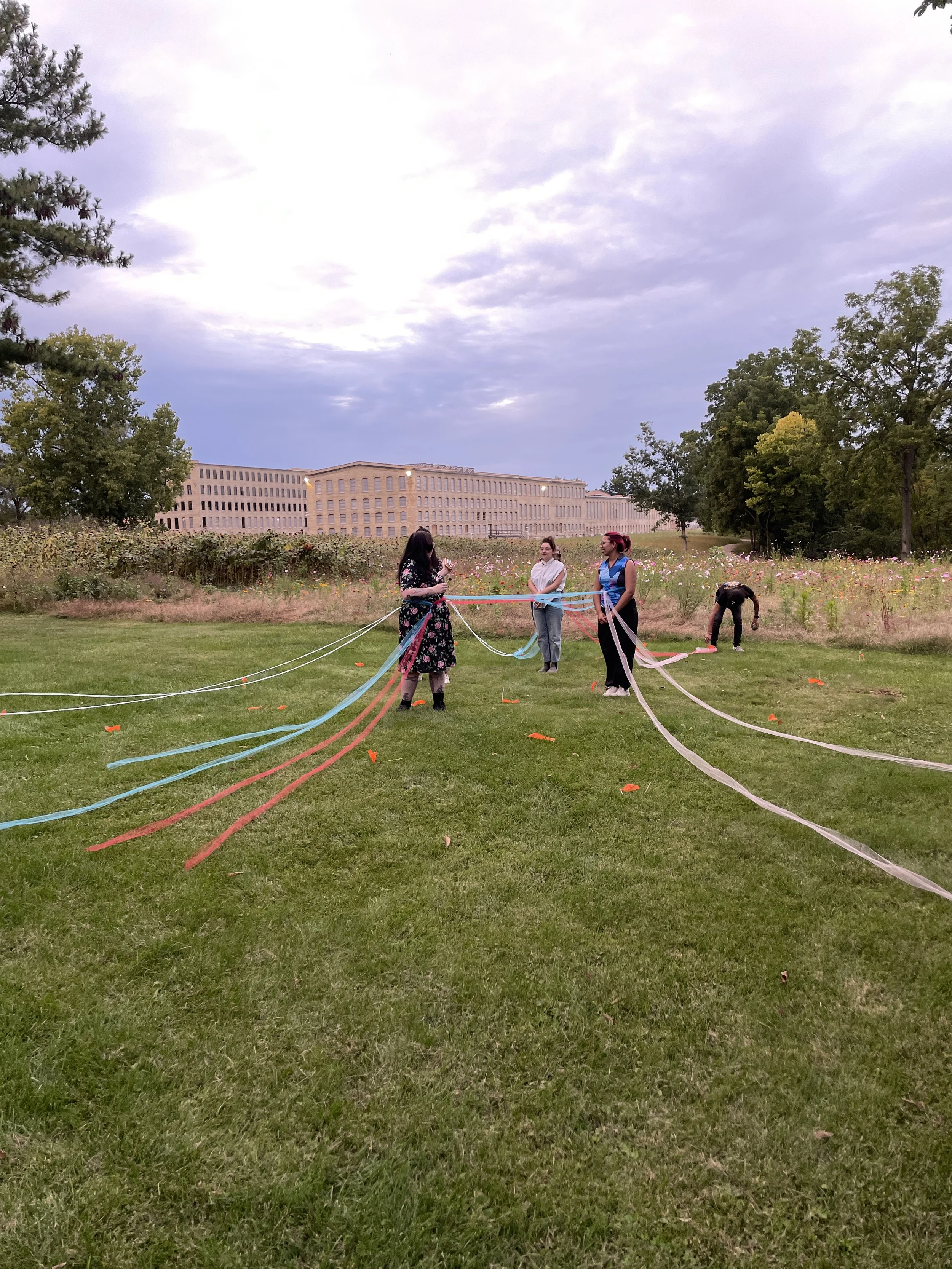 Participants engaging with colorful yarn strands in an outdoor textile installation, Electronic Textile Camp (ETC) co-organized by Craftwork