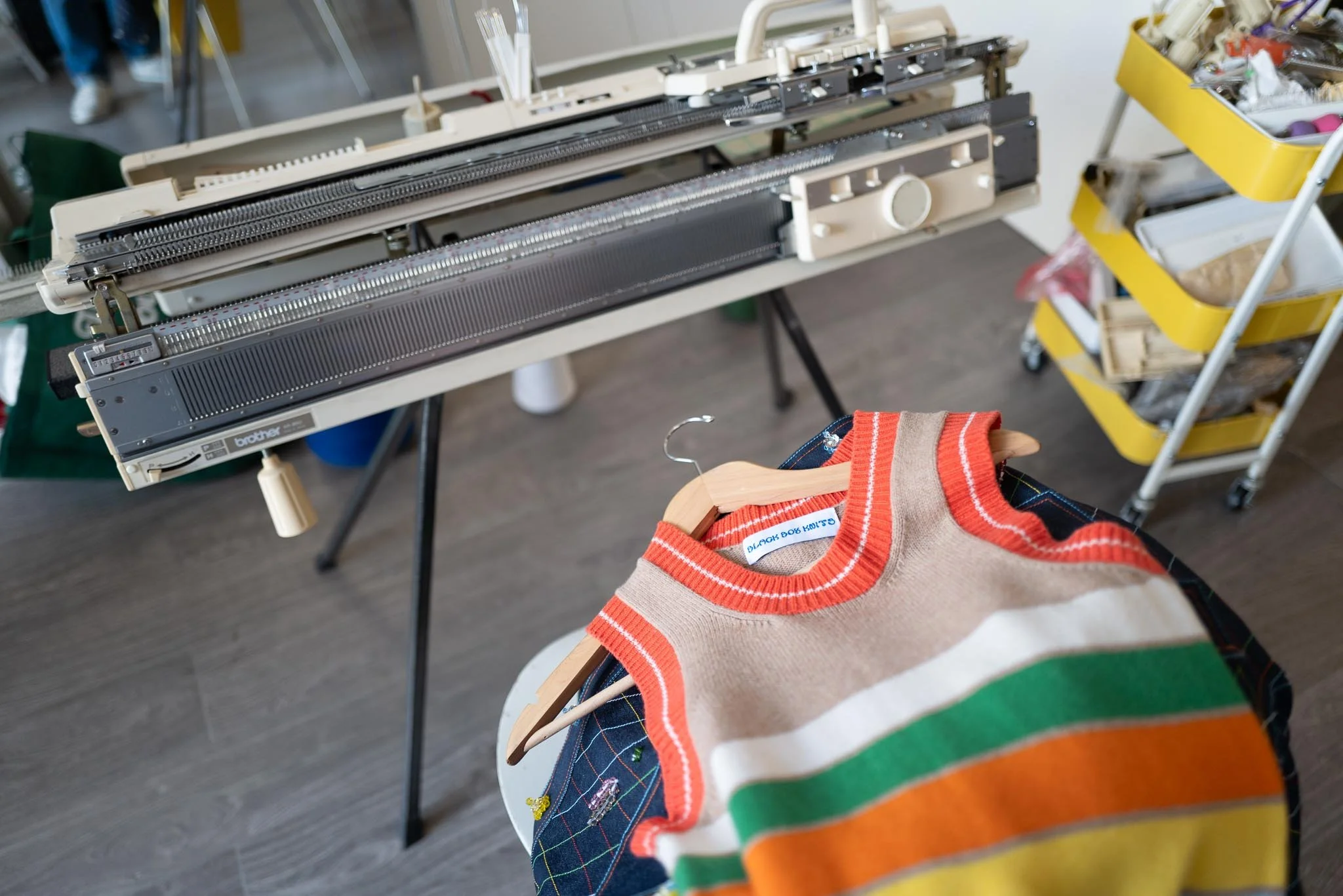 A knitting machine and a finished Black Dog Knits piece on the hanger, mid-production in Jacques Agbobly's studio.
