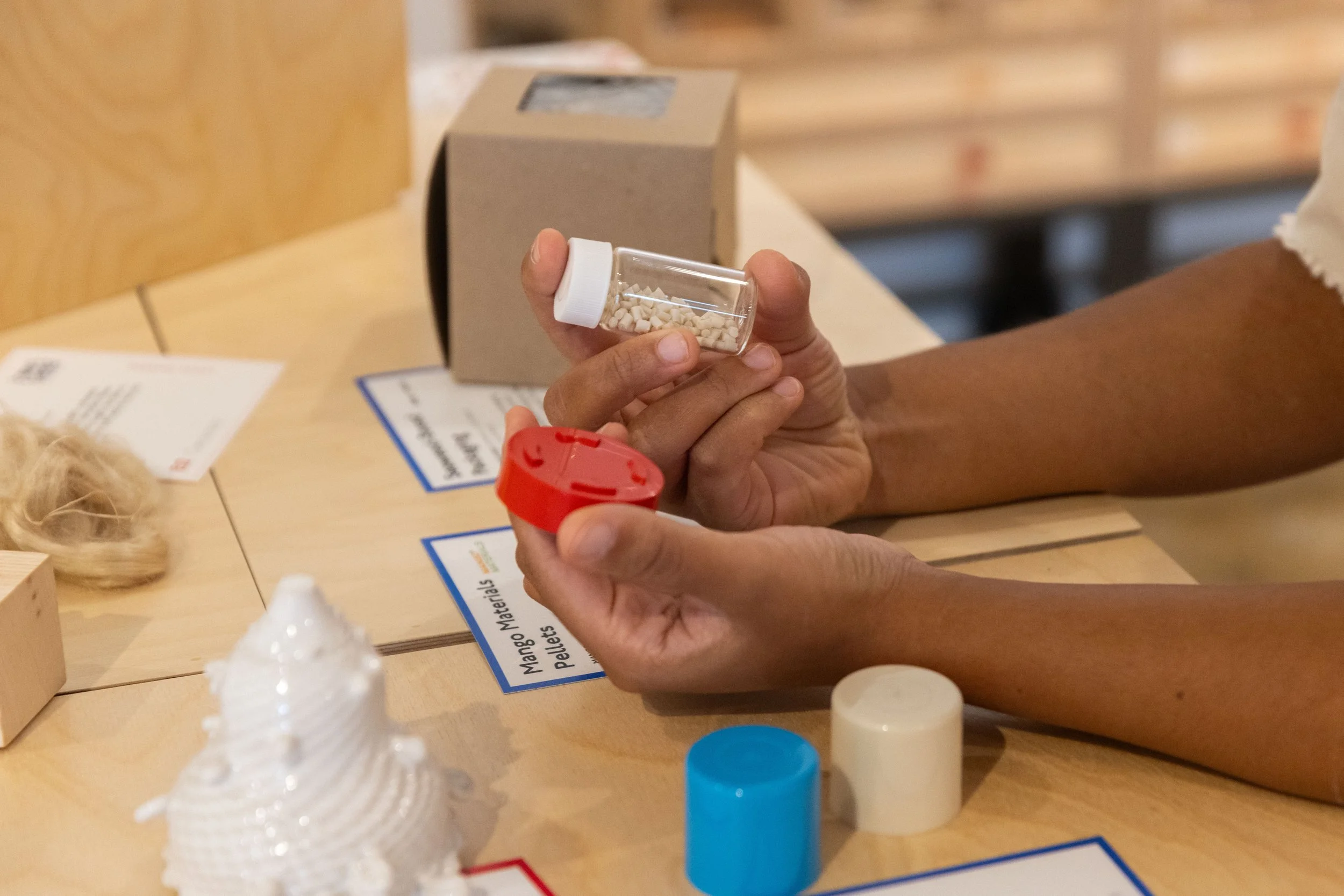 Visitor holding a vial of Mango Materials bioplastic pellets at the  Craftwork-designed Materials Collection interactive display, Center  for Craft