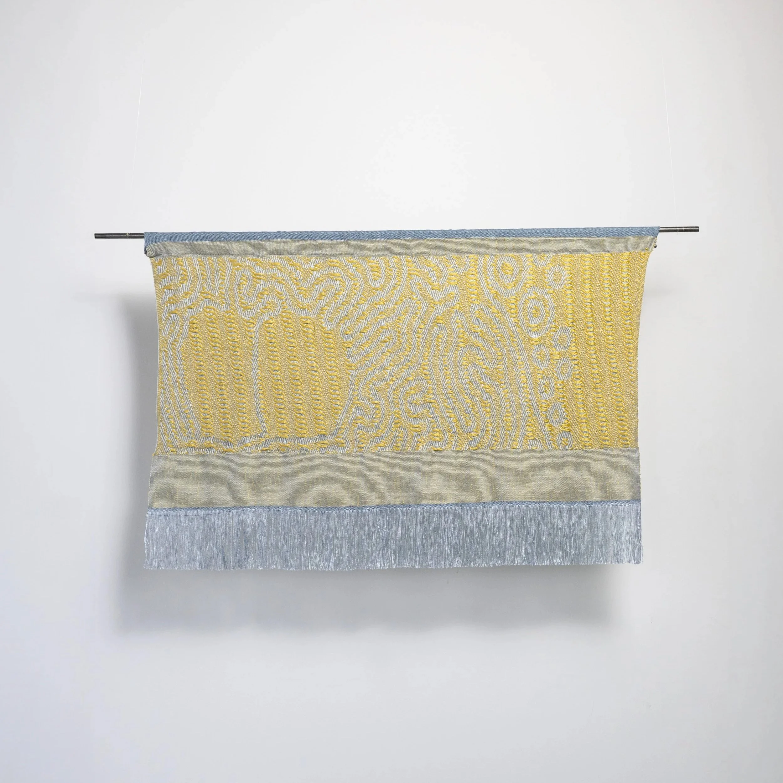Slow Medium woven wall hanging in blue and yellow, showing lichen- inspired dimensional weave pattern with fringe, by Craftwork
