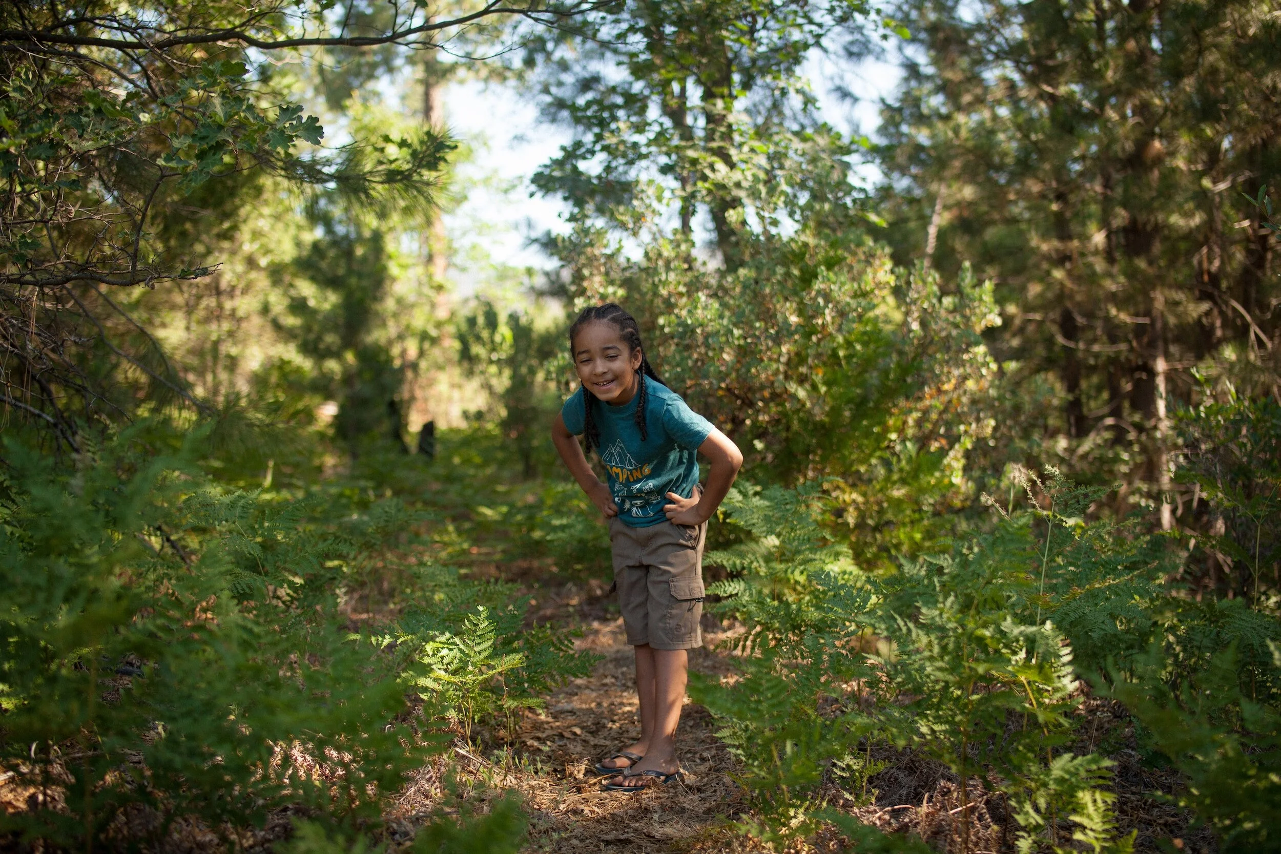 a child standing in the woods smiling