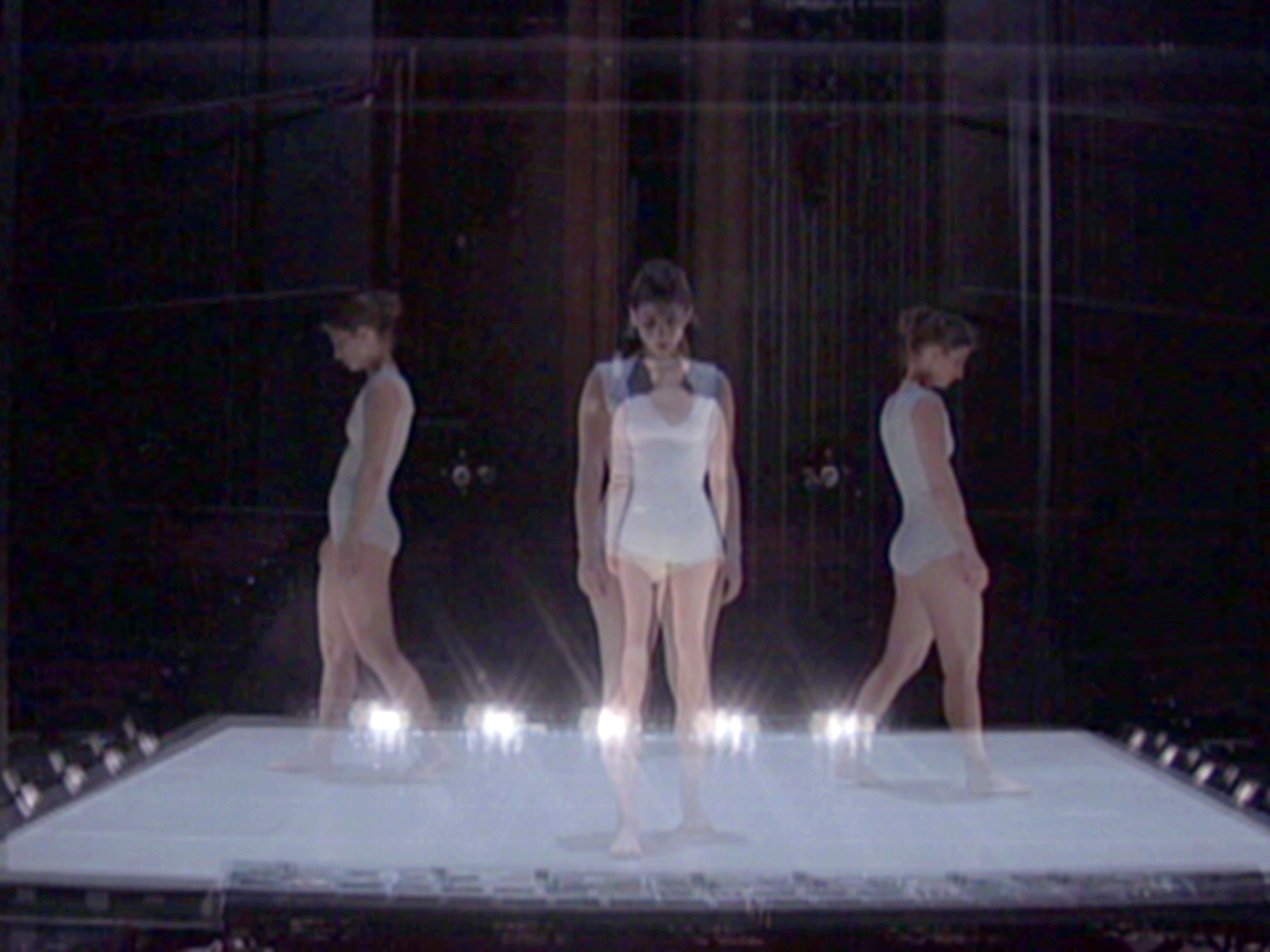 Four images of a performer in a white leotard stepping in each of the four cardinal directions on a square platform stage.