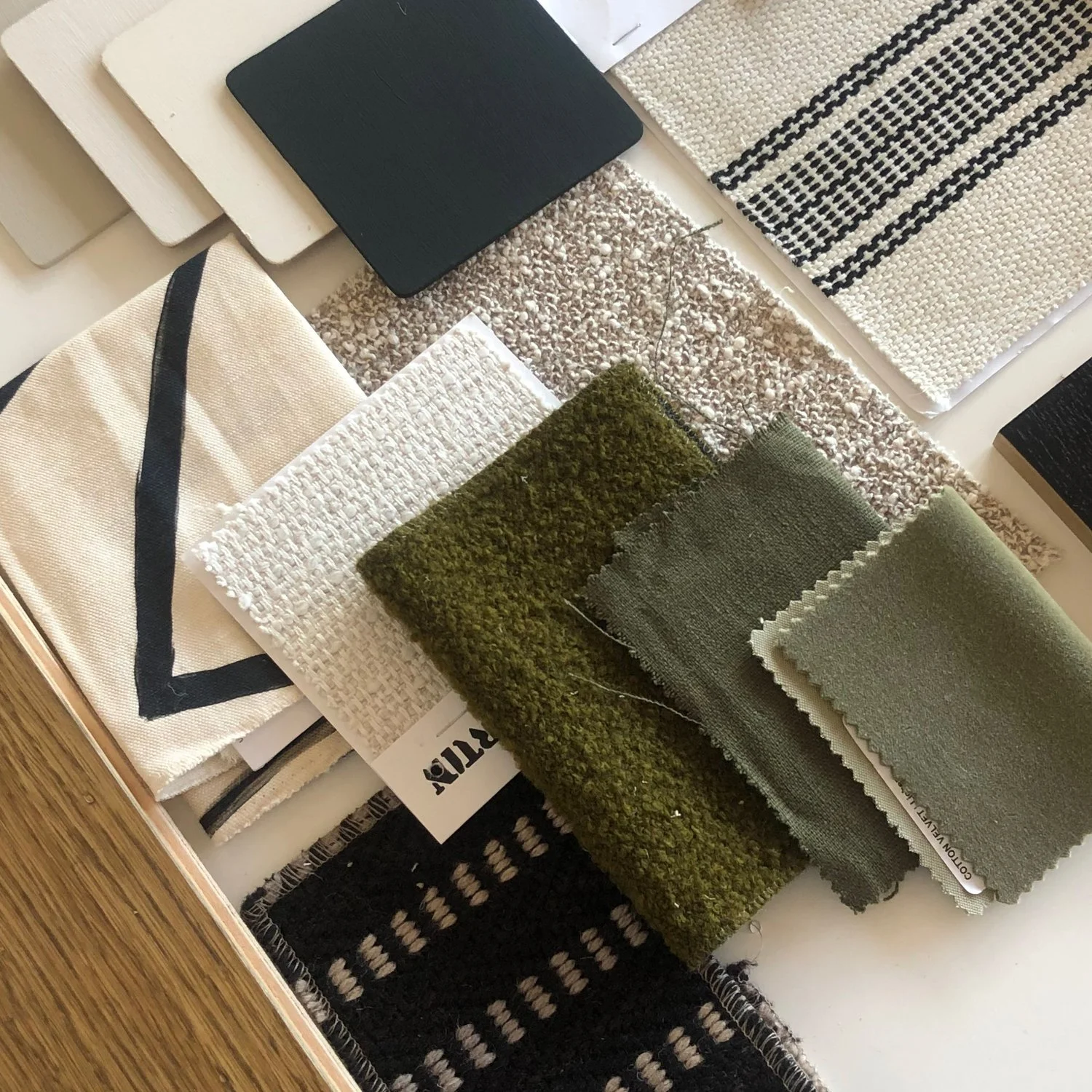 Sample of various fabric swatches and carpet samples in different textures and colors, including beige, black, green, and gray.