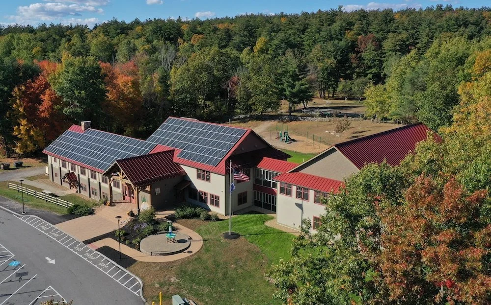 Aerial view of a Windham Woods School designed by RWH Architect showcasing solar panels installed on the roof, highlighting sustainable energy use.