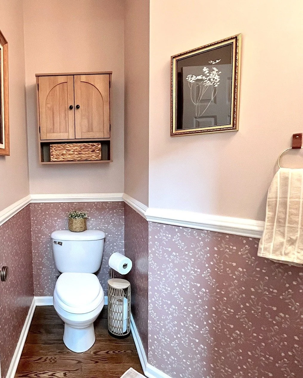 The next installment of this first-floor makeover is a little powder room with a lot of character.

Warm mauve walls, rich wood floors, old-world furnishings, brass accents, and vintage-inspired artwork give this small space a classic, collected feel