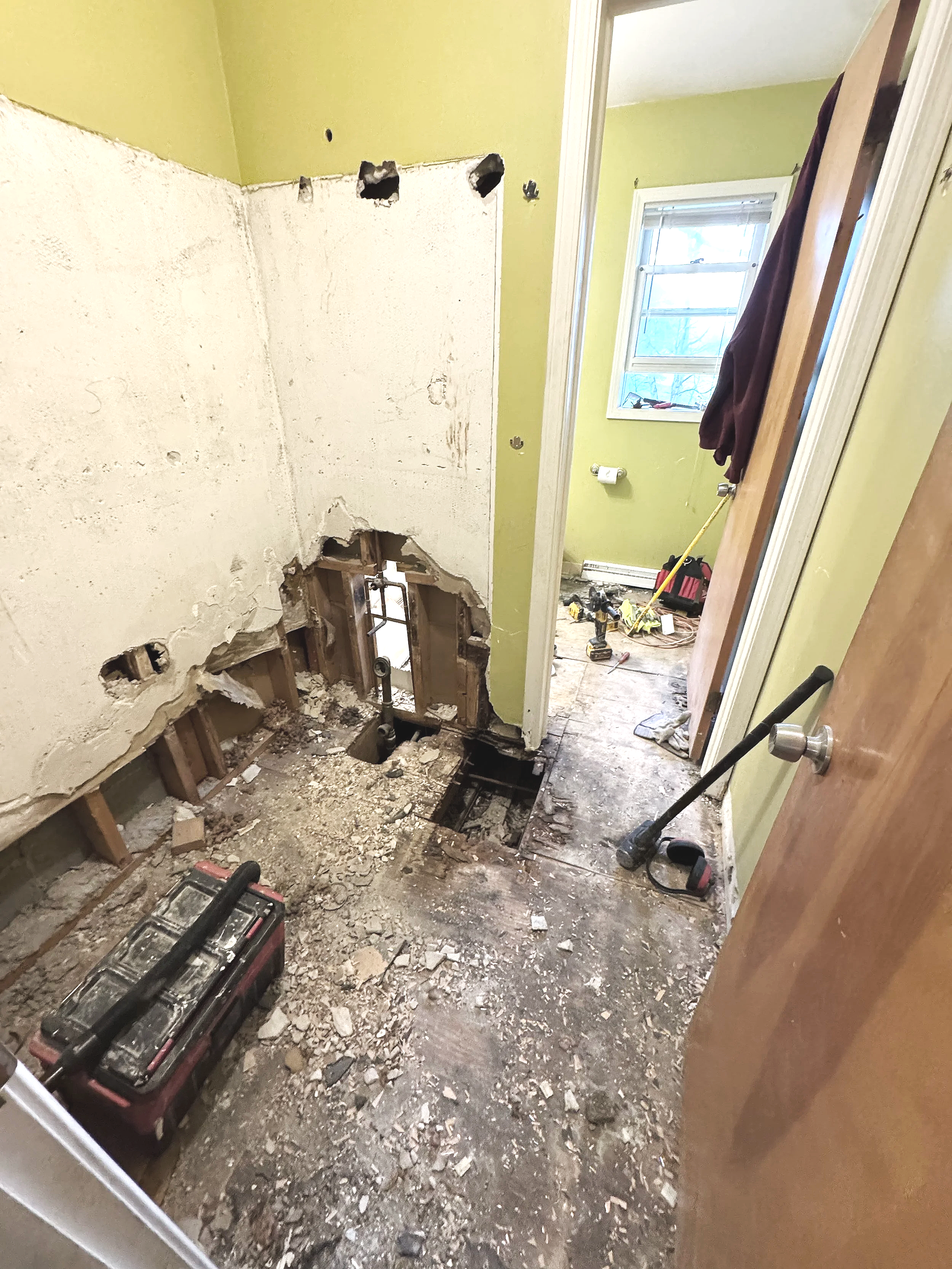 Photo of a 2-chamber bathroom demolition where walls, floors, and fixtures are in varying stages of dismantling