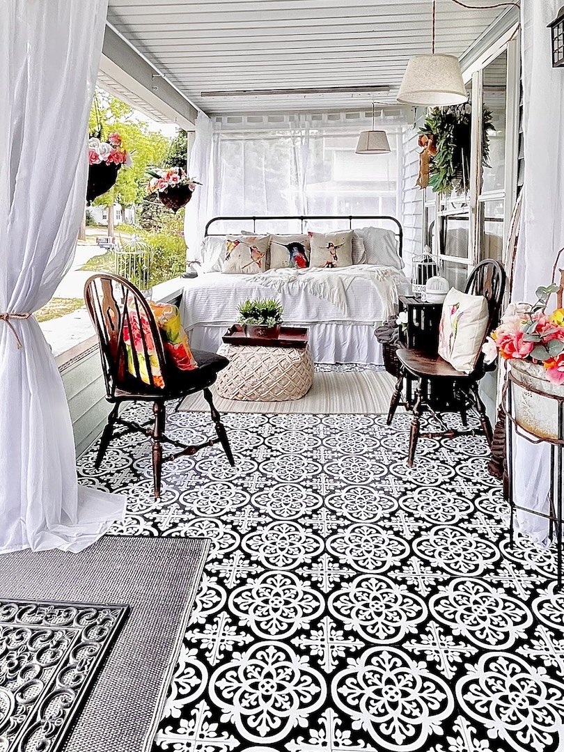 Front porch of a home with a Savannah Georgia inspired sleeping porch of yesteryear with wispy curtains and vintage bed & decor