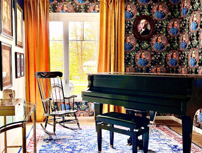 A room that features new paint, wallpaper, furniture, draperies, and decor. Features a black baby grand piano and military themed artwork and wallpaper with George Washington blowing a bubble.