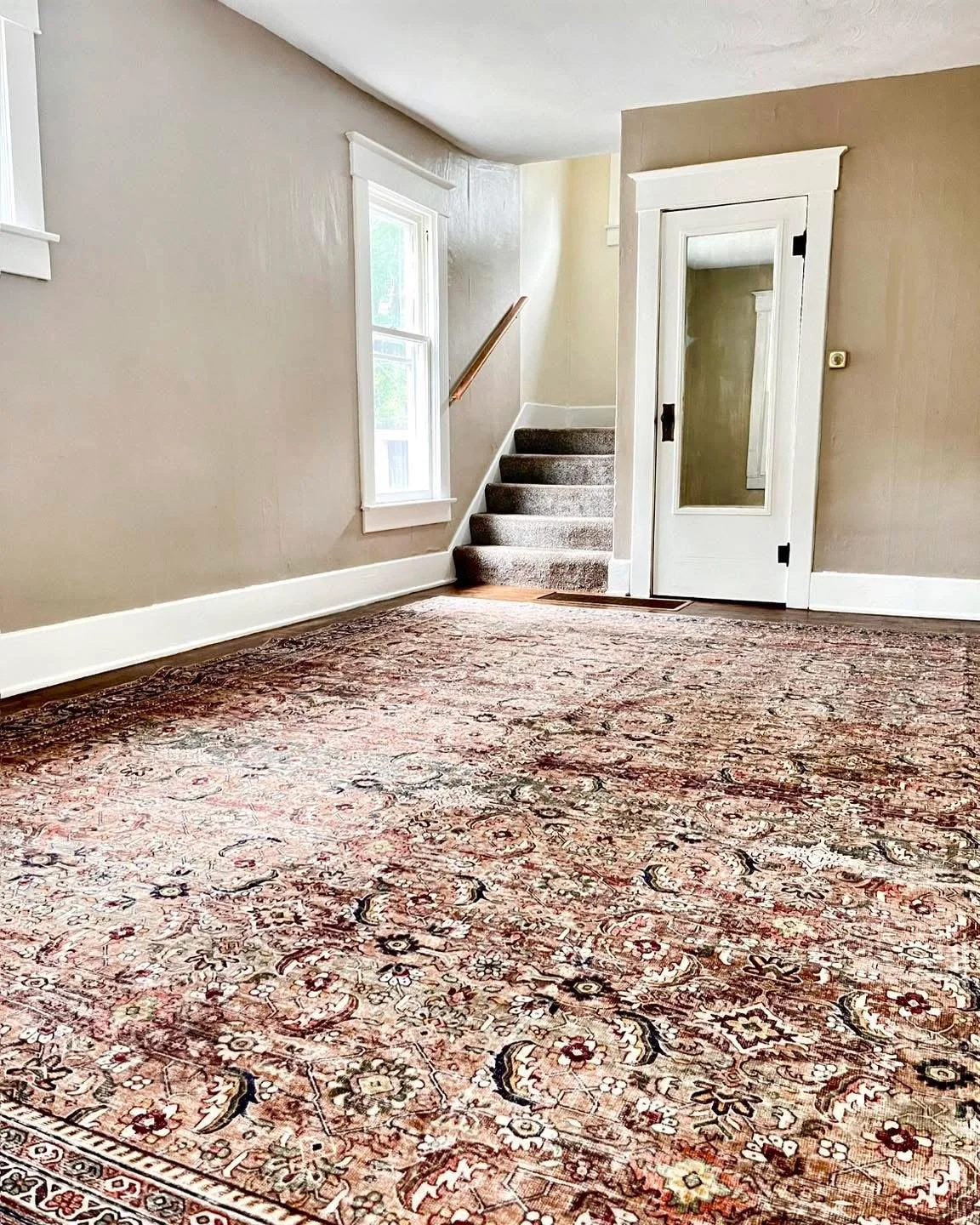 Empty living room of an aged rental house with freshly painted walls, architectural character and a coordinating area rug