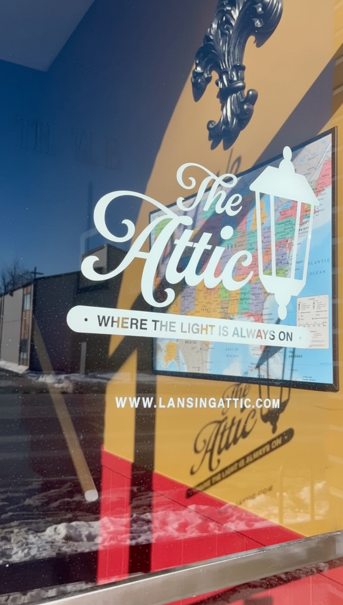 the commercial glass front door of a coworking office space with the logo on the glass casting a shadow on unique decor behind