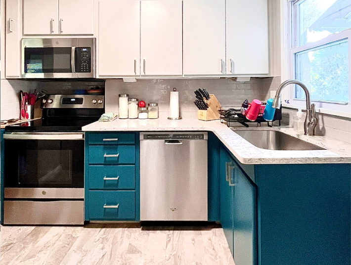 Photo shows a modern kitchen with stone countertop, elegant tile, and two tone custom cabinets in rich contrasting colors