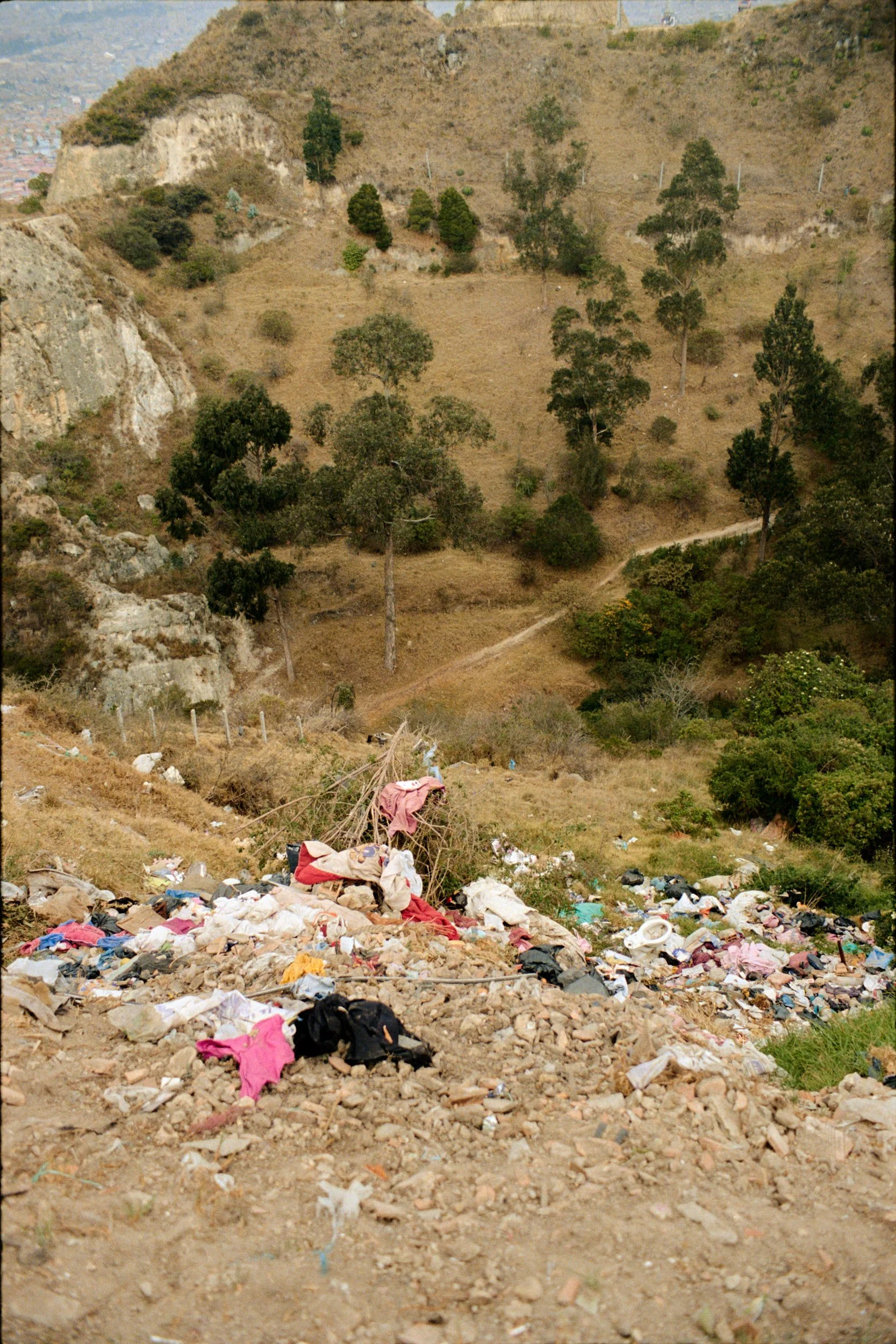 Trash falling down a steep ravine set only feet below the settlement. 
