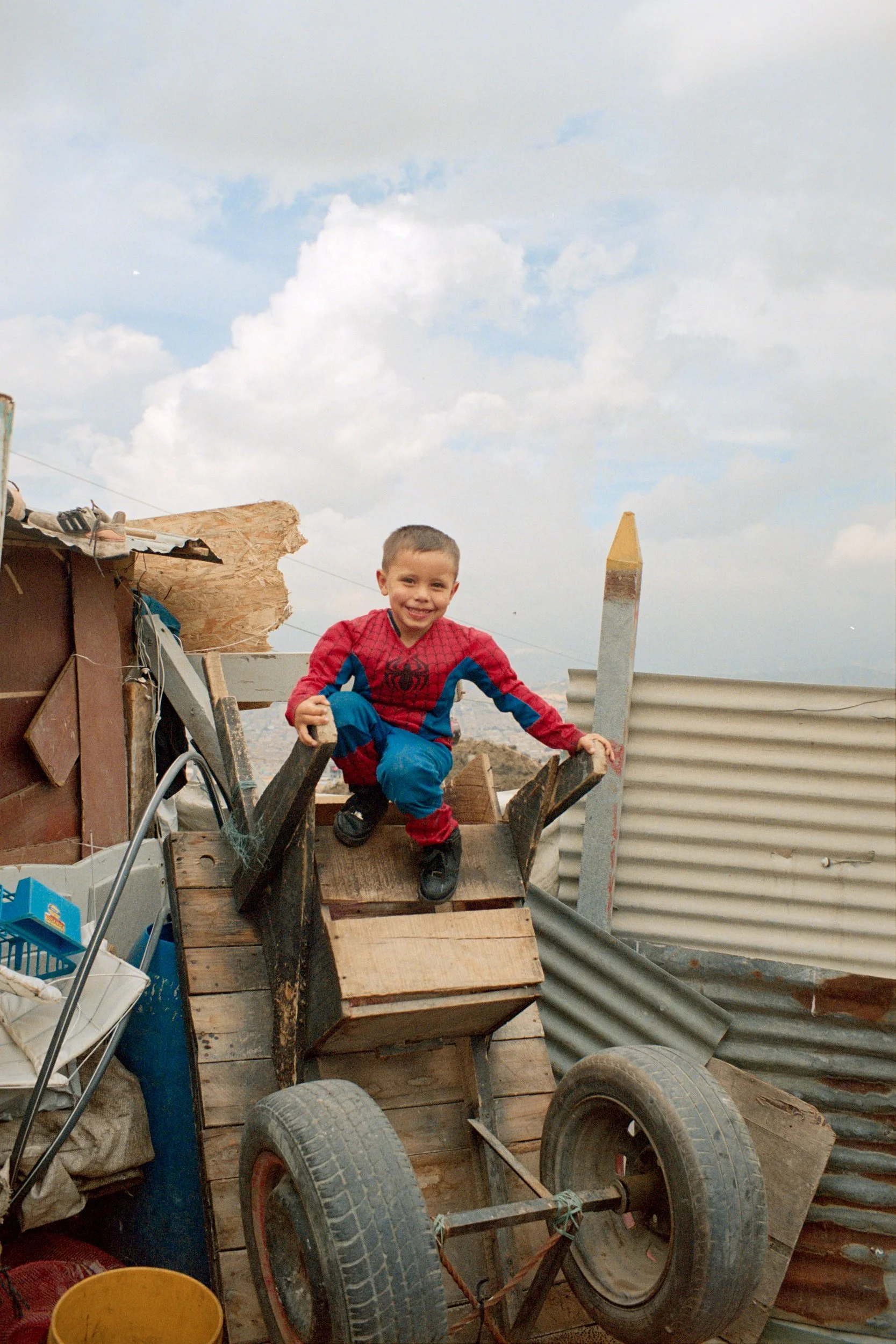 Young boy plays on top of a "zorra", a pushcart meant for carrying trash. 