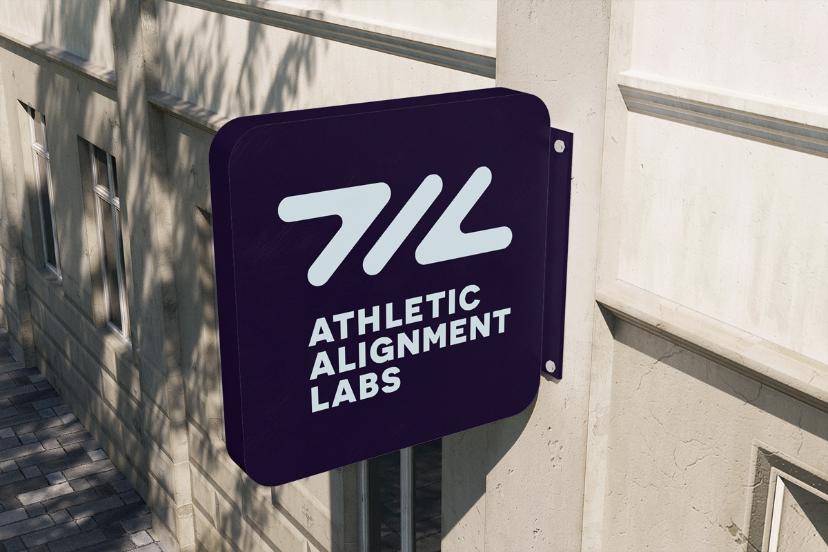 Sign for Athletic Alignment Labs mounted on a building's exterior wall during daytime.