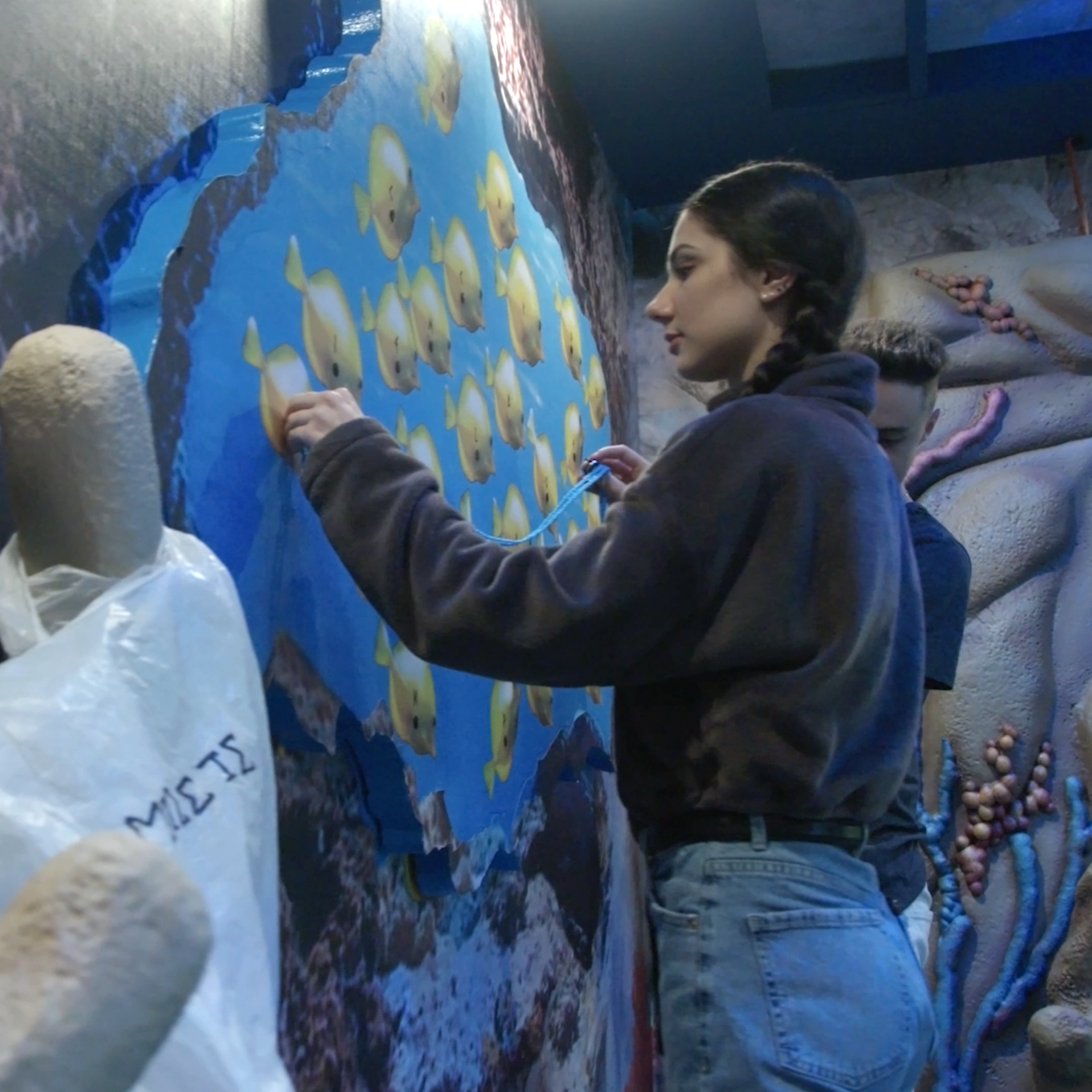 A young adult caucasian girl solving a puzzle in the Poseidon's Promise escape room.