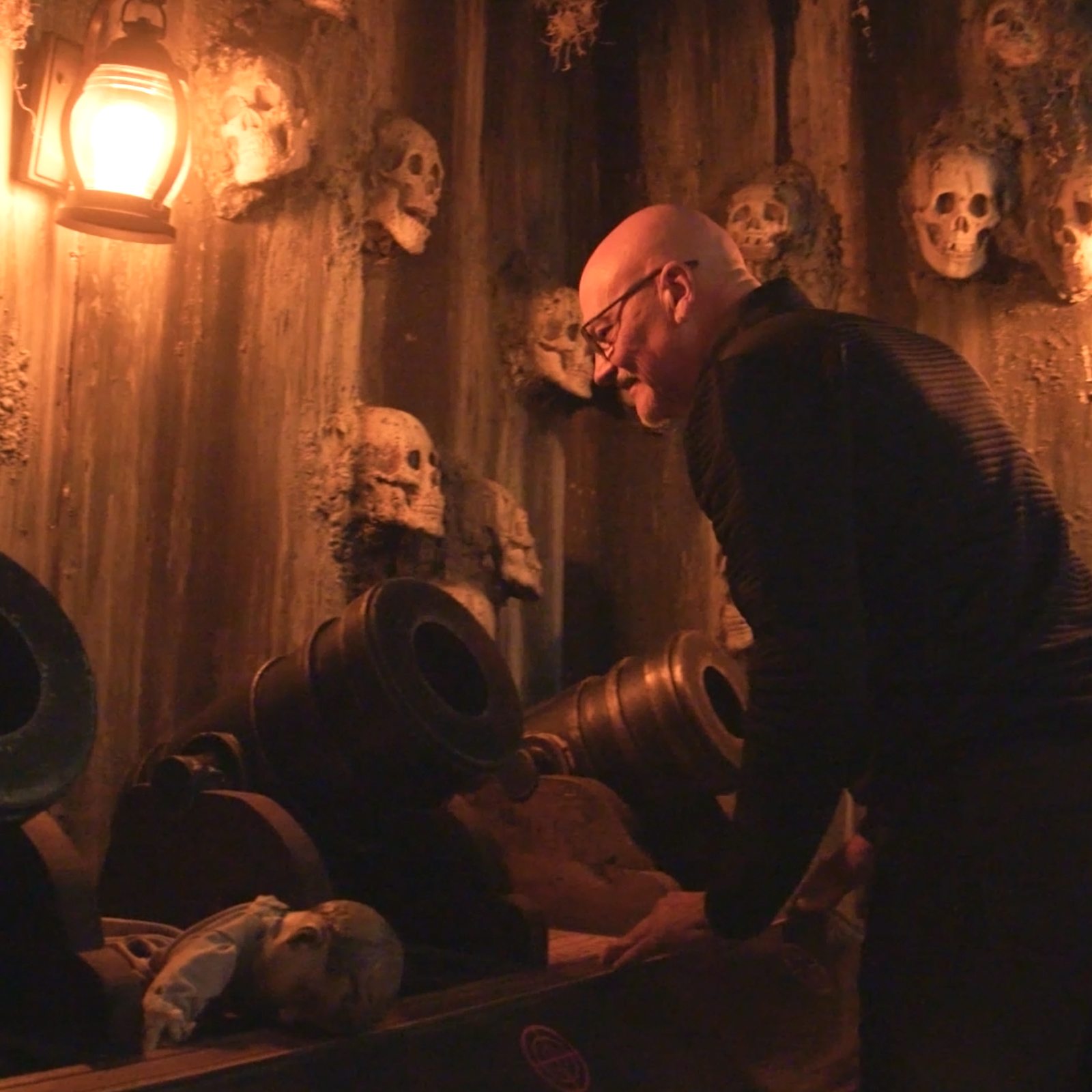 A man looking at cannons and skulls in the Butcher of the Catacombs escape room.