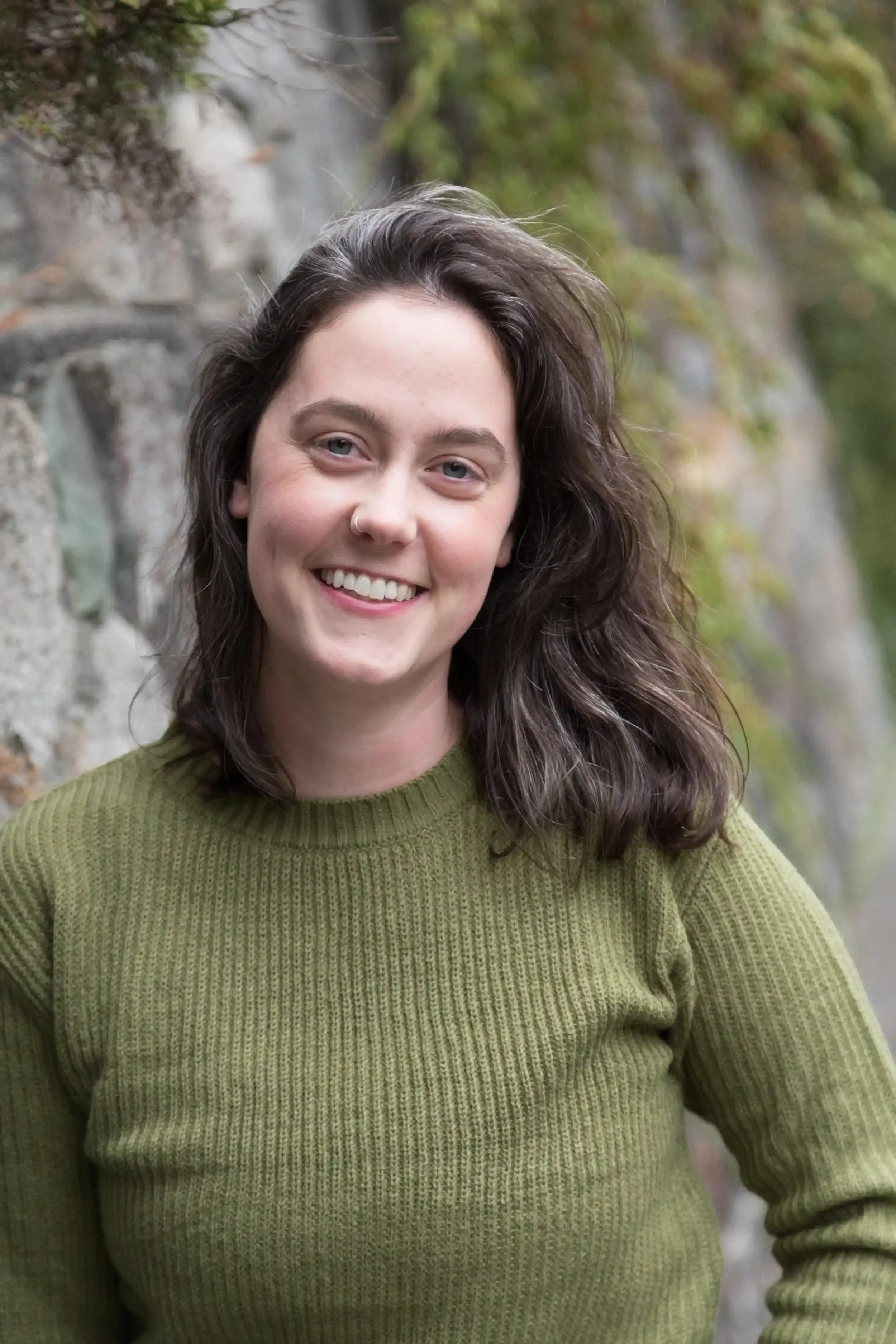 Image of Kate smiling in a green sweater in front of a wall