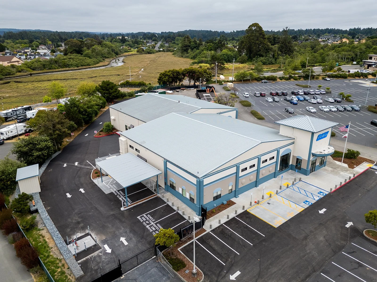 Aerial view of back drive test car port, gate, fence, and parking area. 