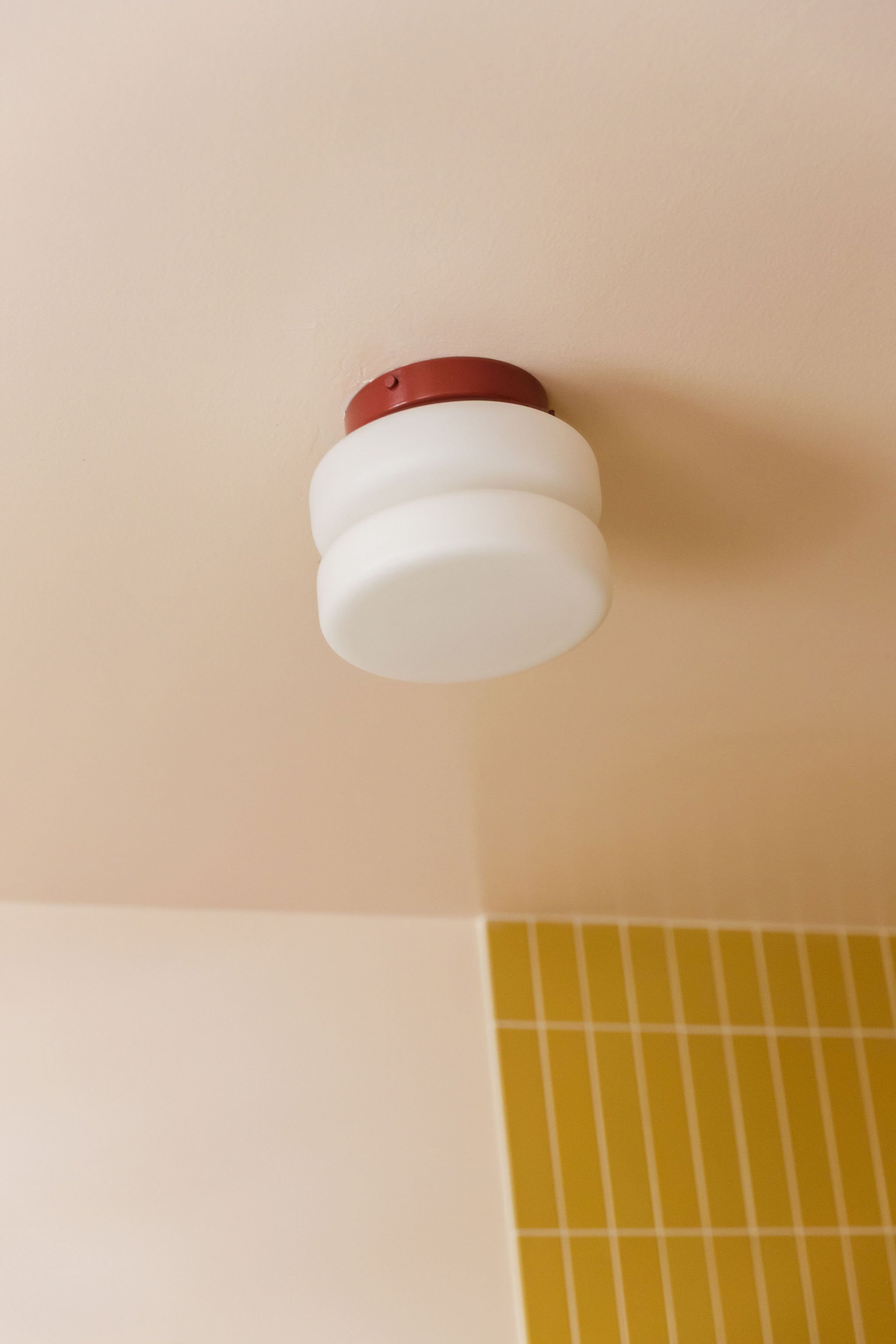 Ceiling light fixture with a rounded, cloud-like shape, maroon base, and white glass shade, seen from below.