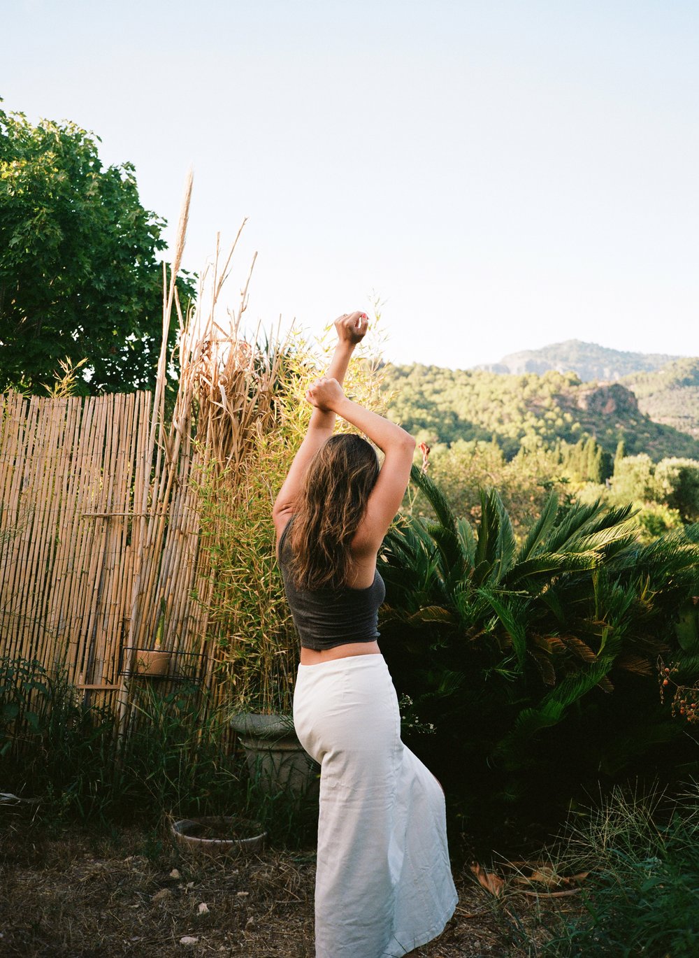  woman holding her hands up in a garden in Mallorca, Spain. 