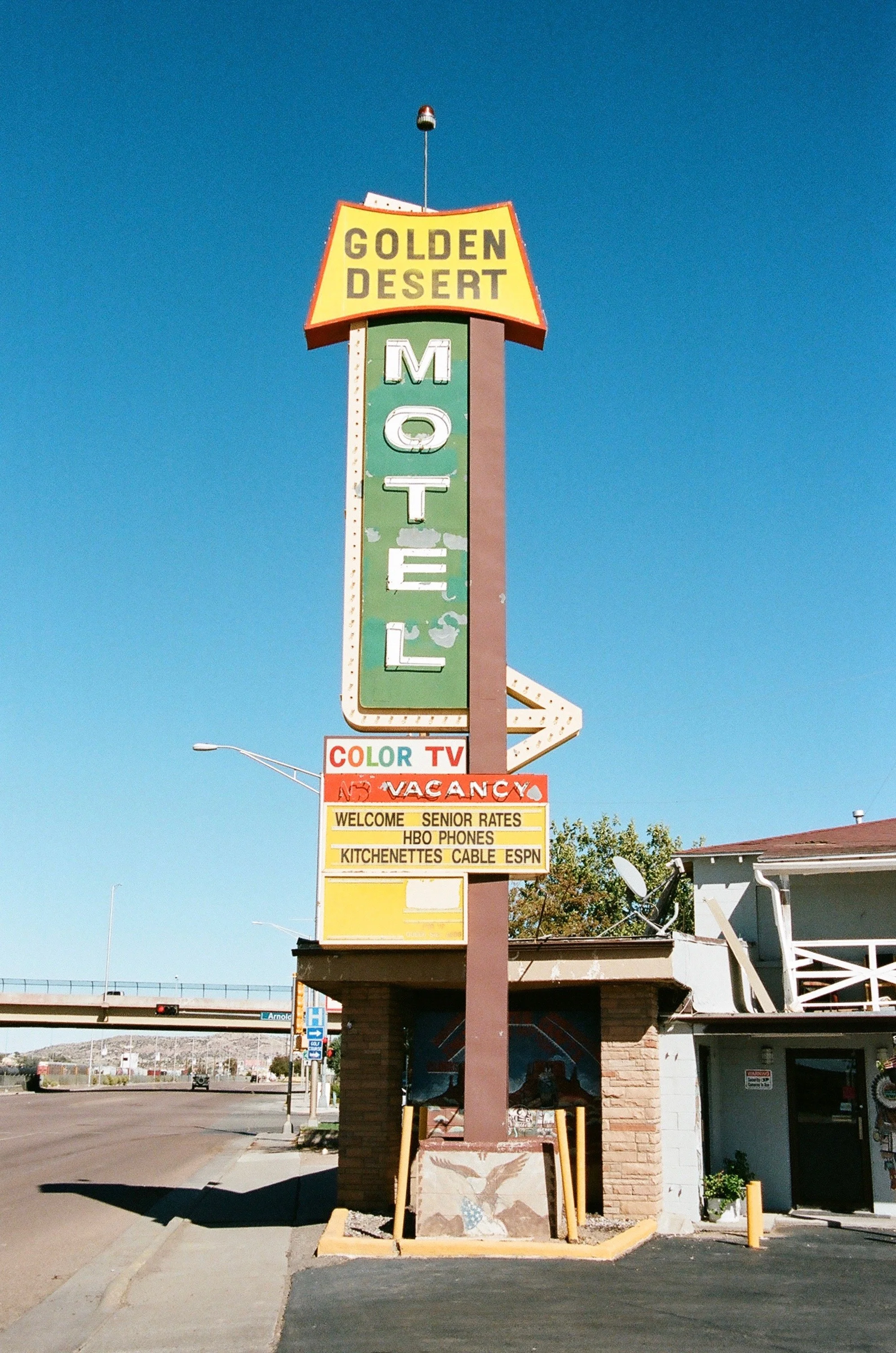 Vintage motel sign for Golden Desert Motel with a bright blue sky background.