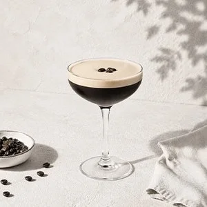 Espresso Martini i coupeglas med krämigt skum och kaffebönor på toppen – en elegant kaffecocktail med fyllig espresso och kaffelikör.