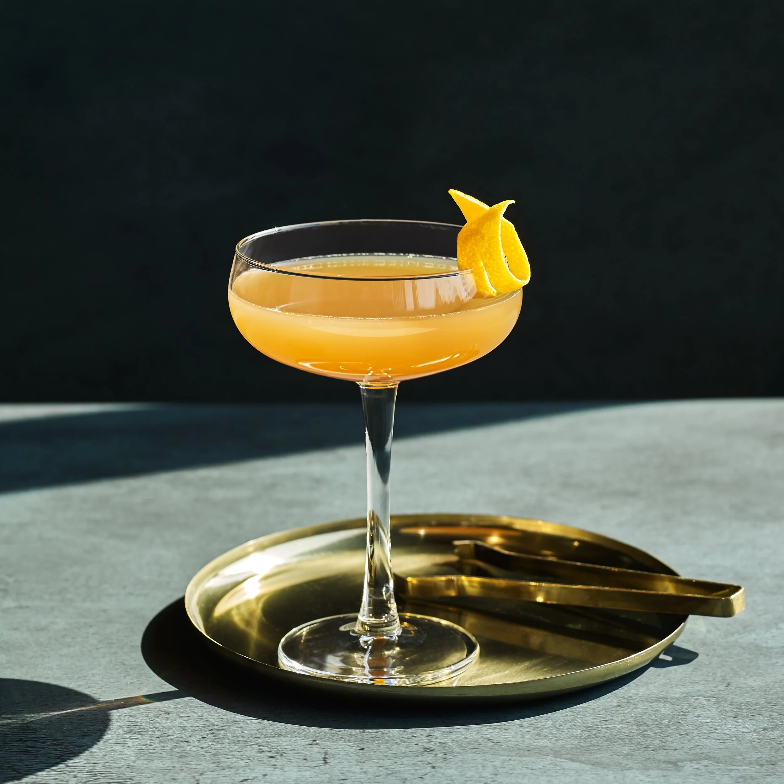 Sidecar cocktail med citrus i coupeglas mot mörk bakgrund.