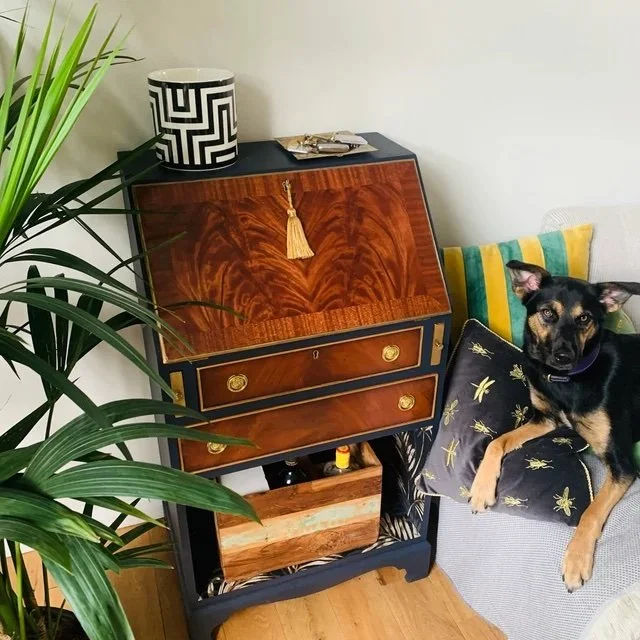Living room with a vintage wooden bureau, hand painted dark blue with original wood thats been varnished. Gold tassel