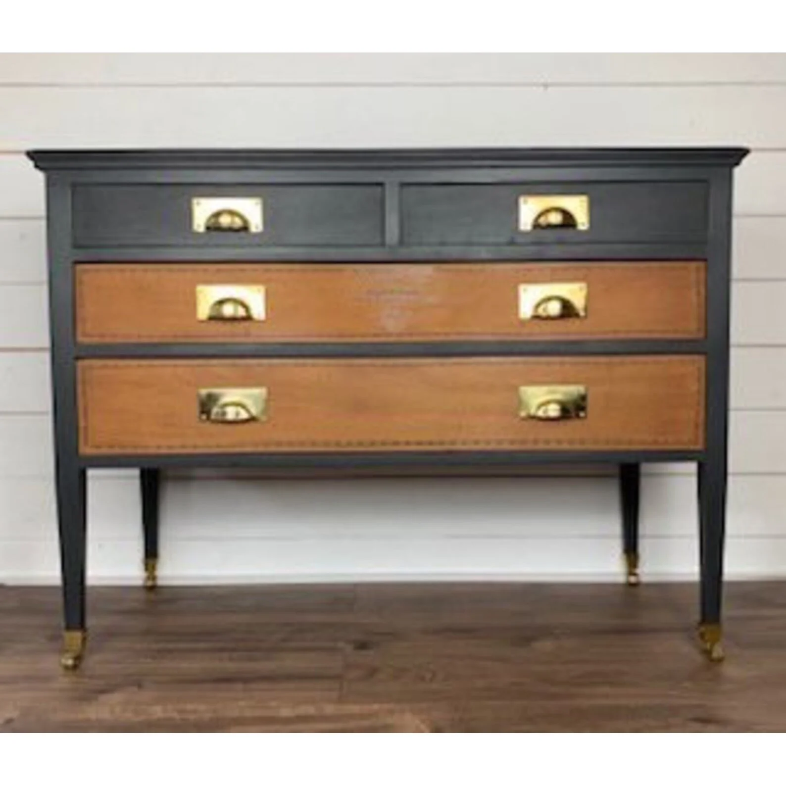 Vintage dresser with four drawers, featuring dark blue frame, brown drawer fronts, and brass handles, on dark tapered legs.