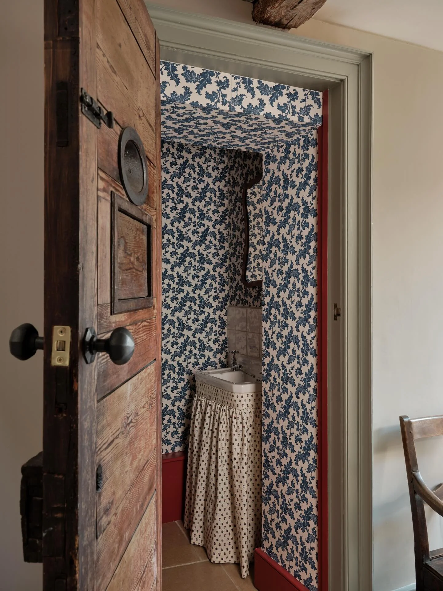 Once a cell in a sheriffs house, now a downstairs loo featuring the original cell door with bolts, hatches and a peep hole. 

A thoughtfully designed small space, elevated with a statement wallpaper, a feminine vanity skirt and a bold frame to tie it