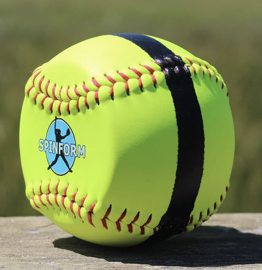 A neon yellow soft baseball with red stitching and a black stripe, resting on a wooden surface, with a blurred outdoor background.