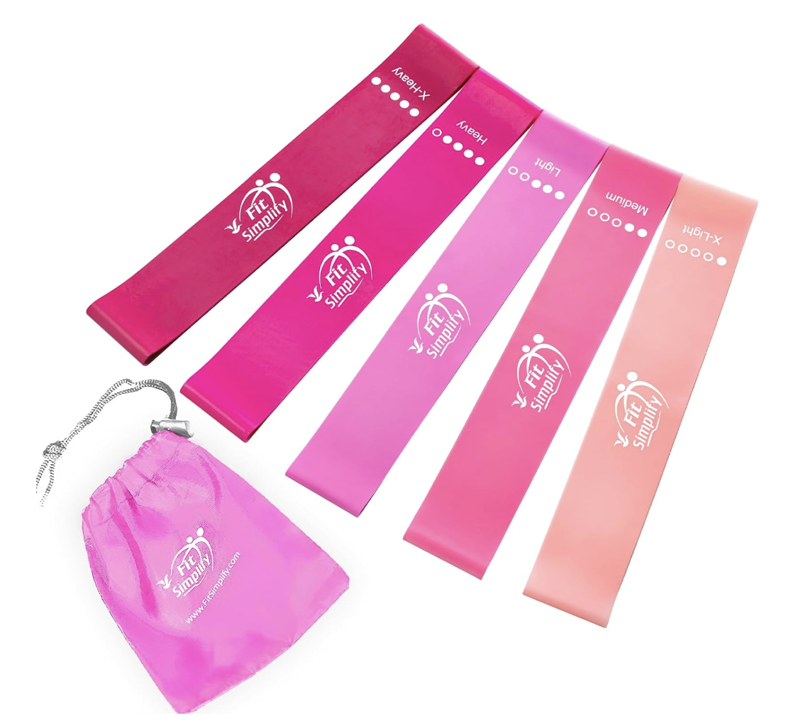 A set of four pink exercise resistance bands labeled from light to heavy with a pink drawstring pouch beside them.