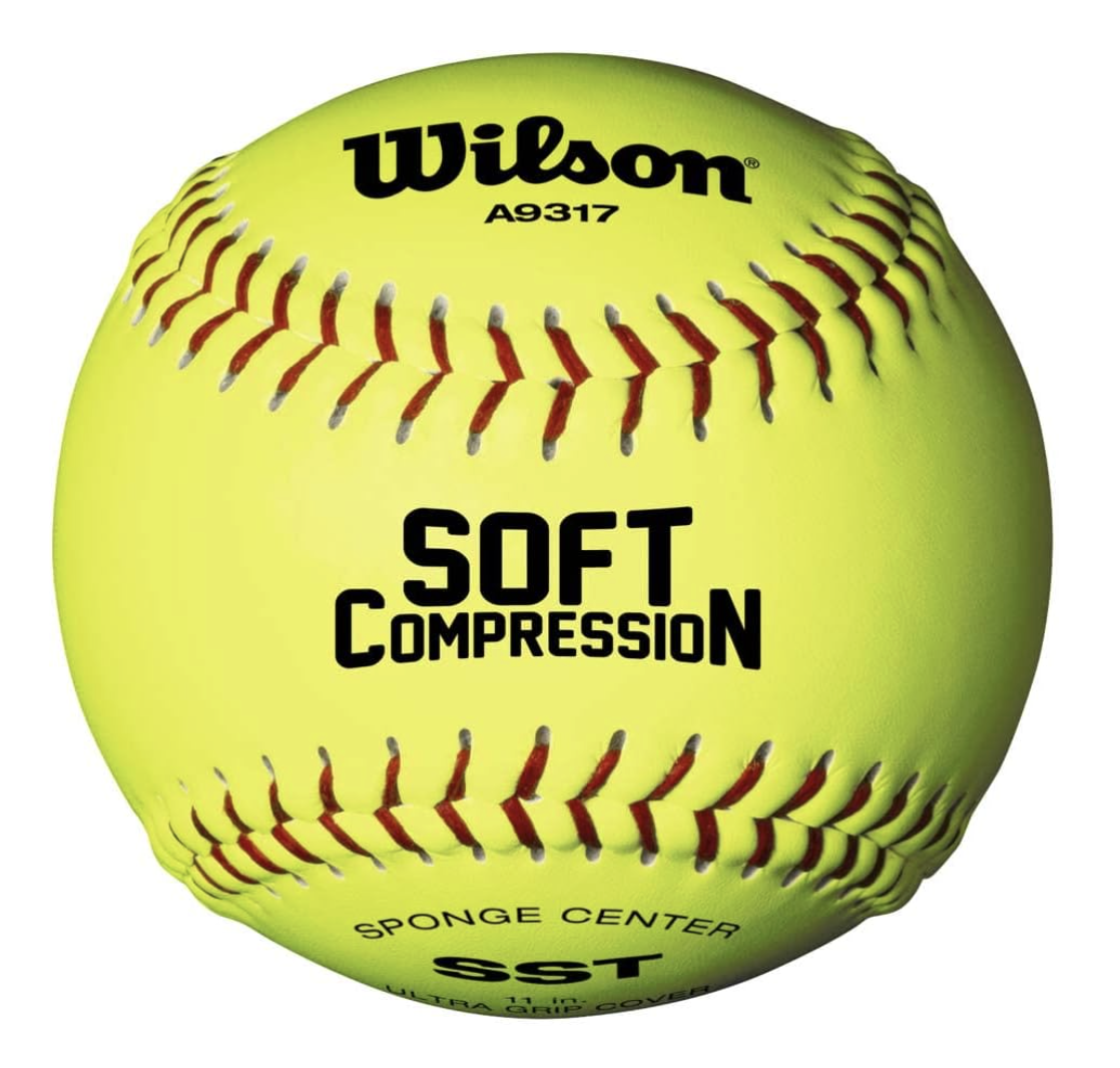 Bright yellow softball with red stitching, displaying the words "Wilson", "SOFT COMPRESSION", and "SPONGE CENTER SST" in black lettering.