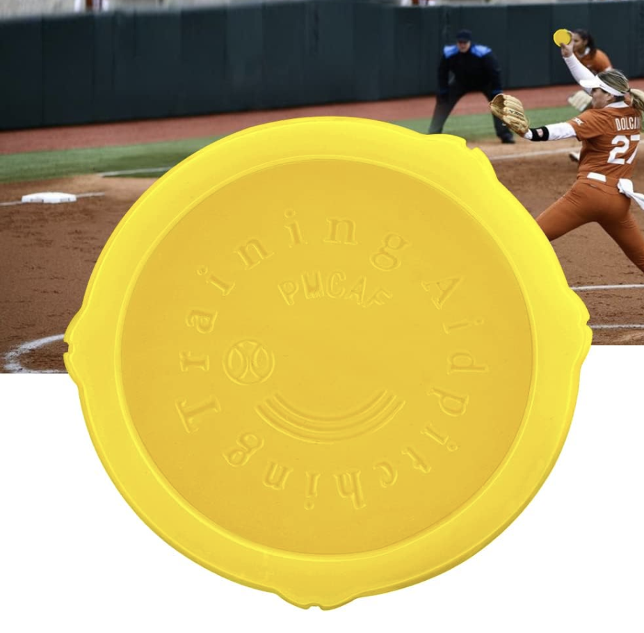 Yellow plastic baseball pitching target with a smiley face and the words "Pitching" and "Training" hints in the foreground. In the background, a softball game is in progress with a player in orange uniform pitching.