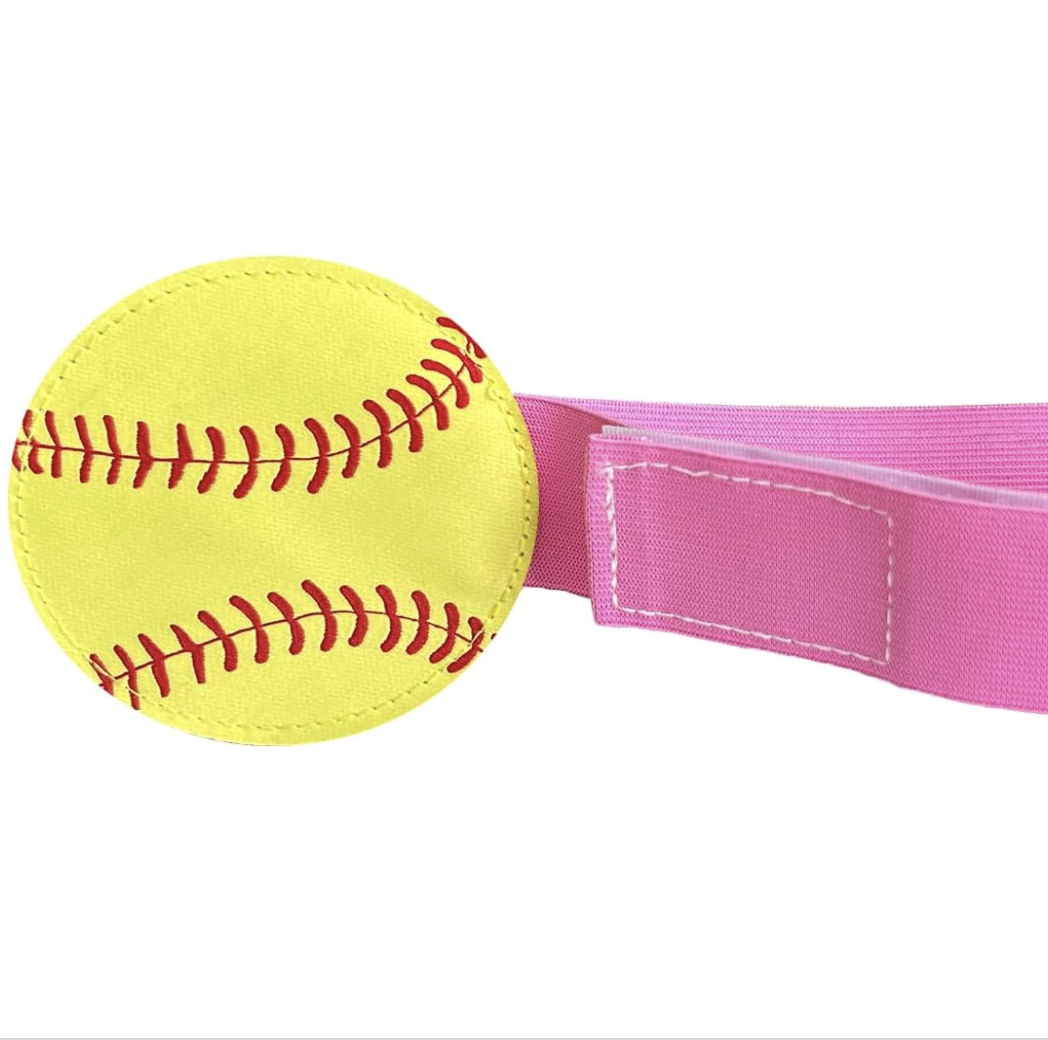 Close-up of a softball attached to a pink strap, used as a wrist or ankle accessory.