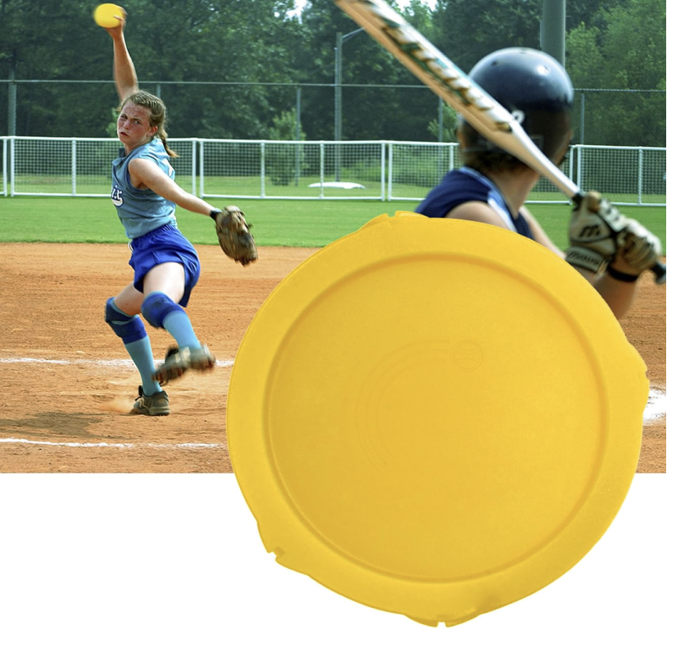 A girls' softball game with a pitcher in action and another player preparing to bat on a baseball field with green trees in the background, and a yellow plastic disc in the foreground.