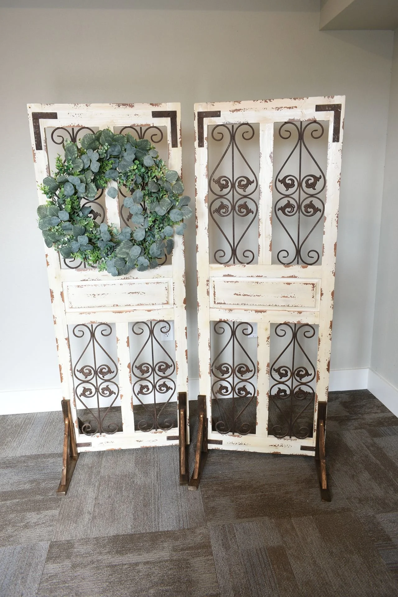 Two vintage wooden panels with ornate wrought iron scrollwork leaning against a wall.