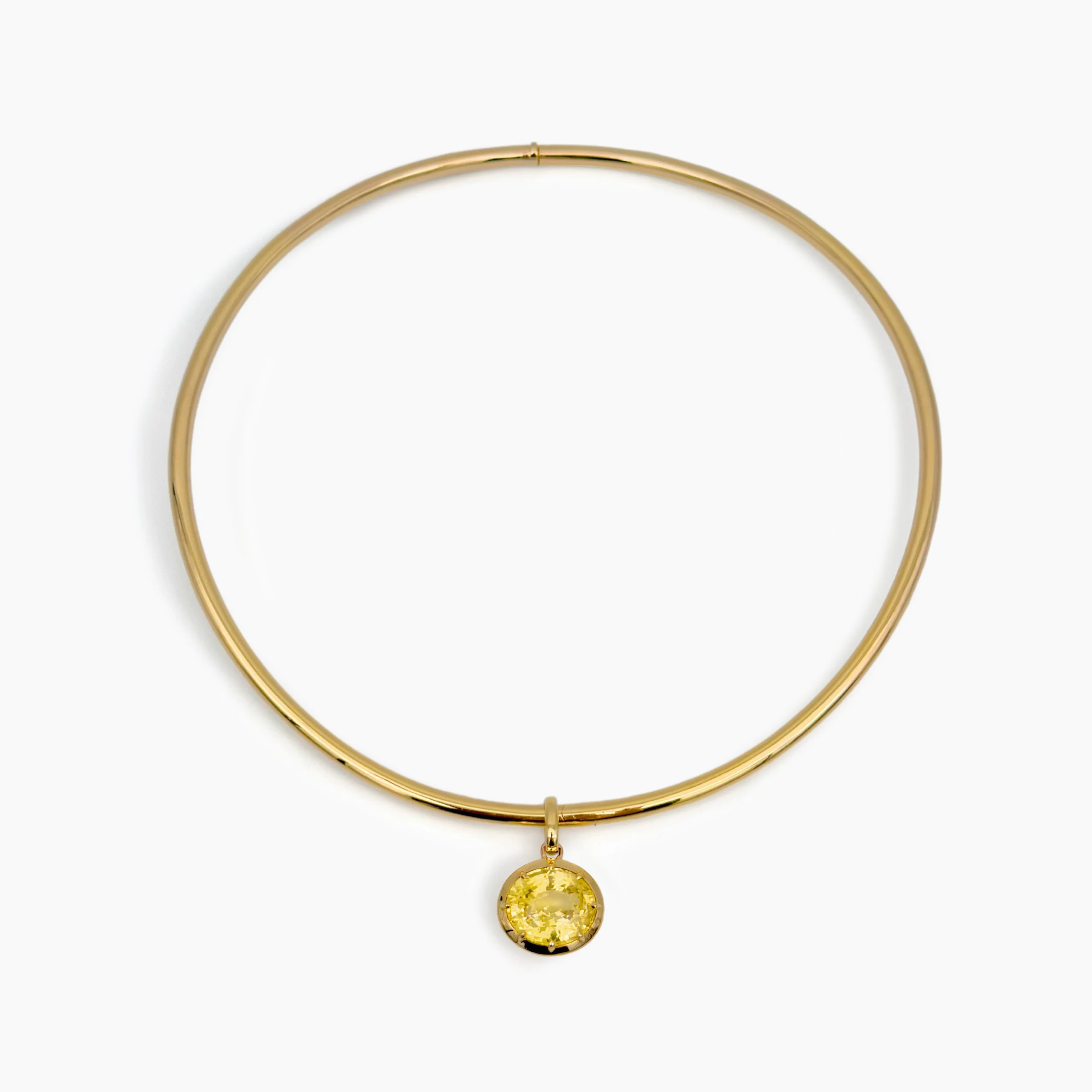 Gold necklace with a yellow gemstone pendant on a white background.